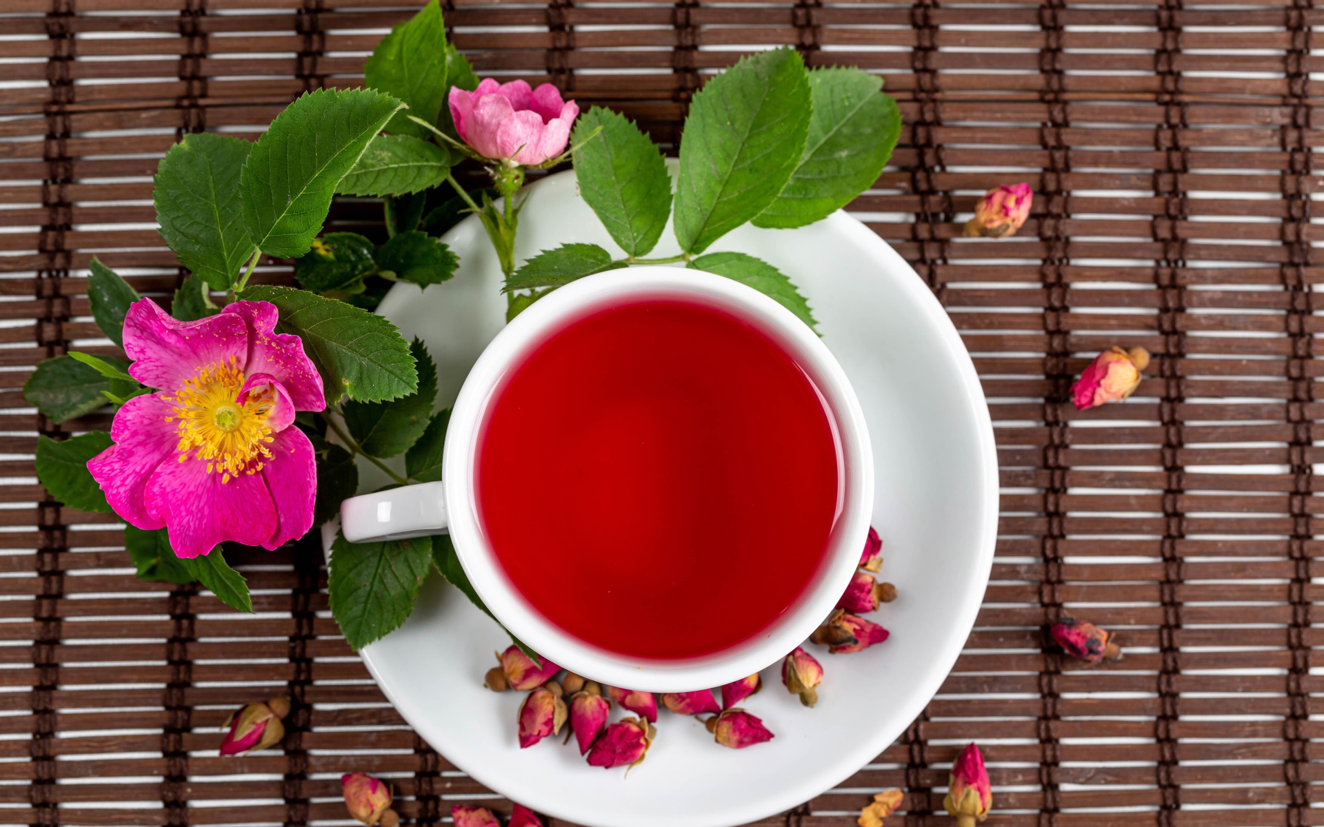 Красный чай с шиповника на столе с цветами