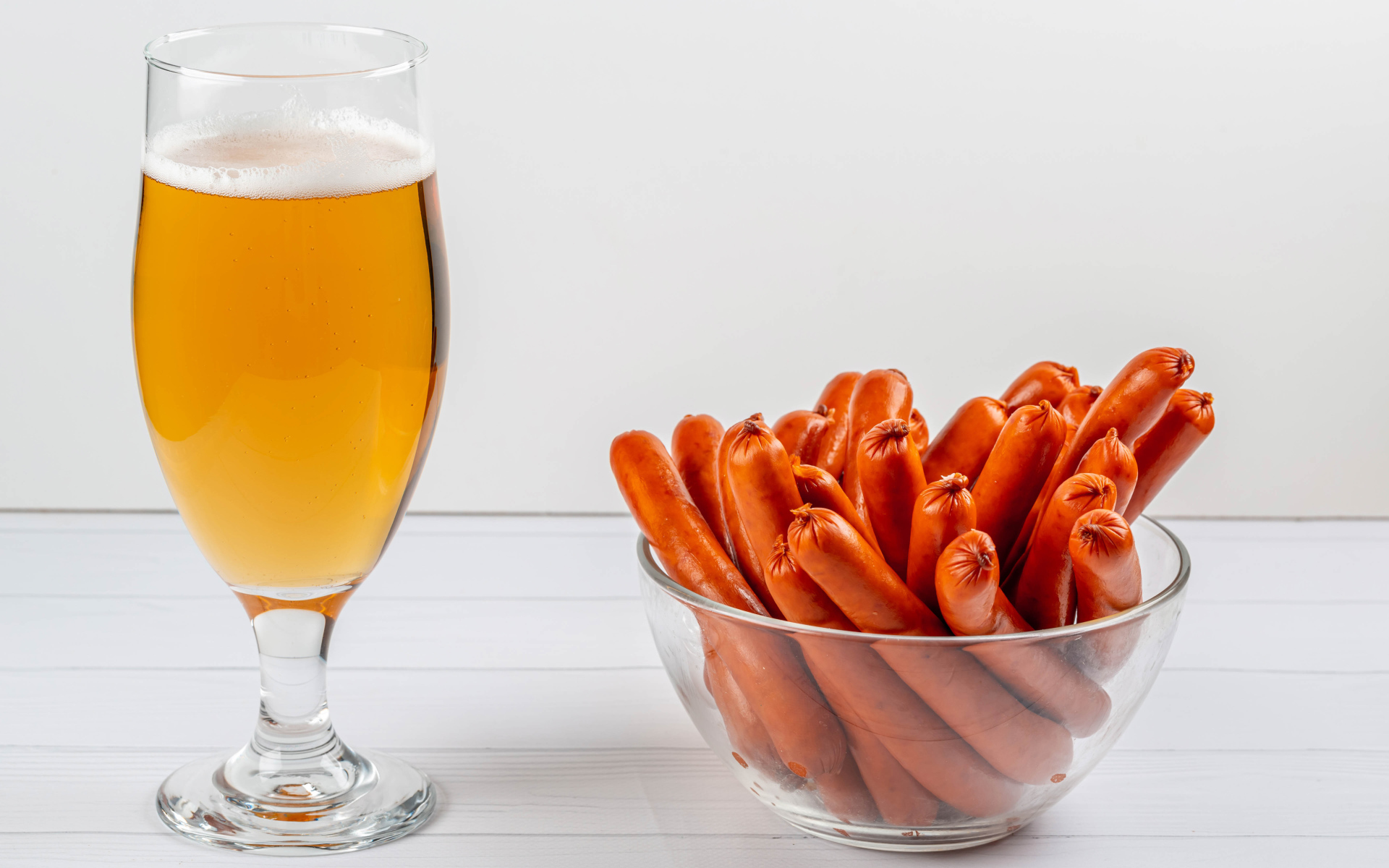 Вкусные сосиски на столе с бокалом пива