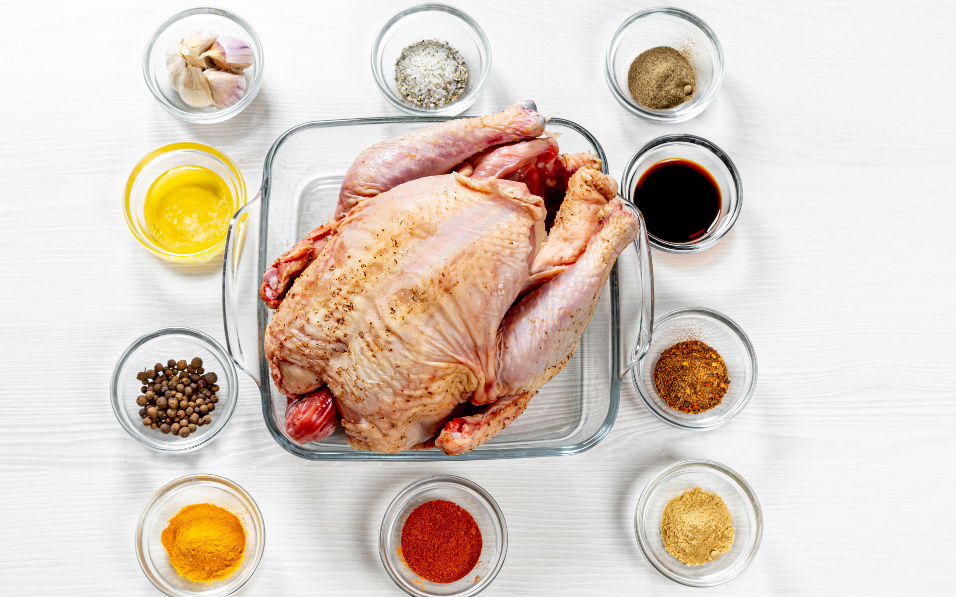 Свежая курица на противне на столе со специями 