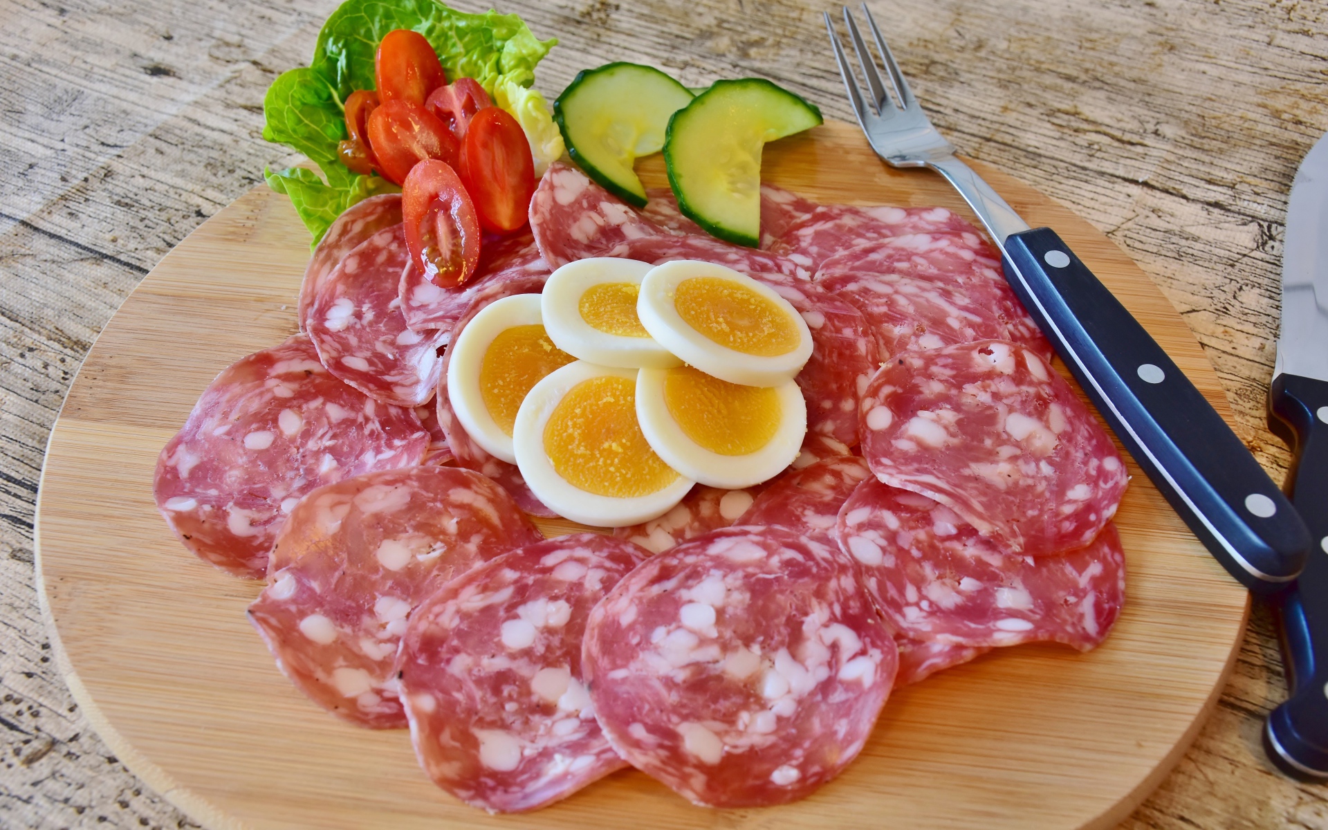 Колбаса салями на доске с яйцами и овощами