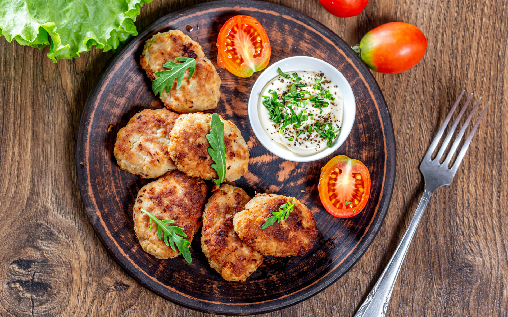 Вкусные котлеты на столе с соусом и помидорами