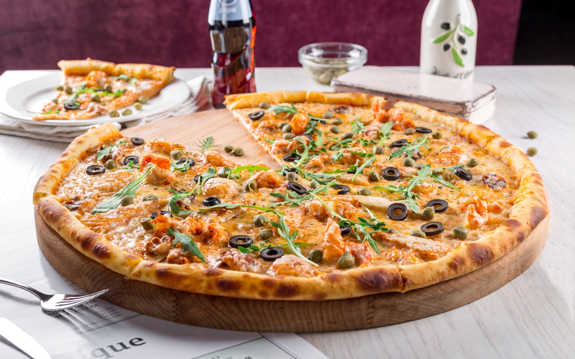 Большая аппетитная пицца с маслинами на столе в кафе