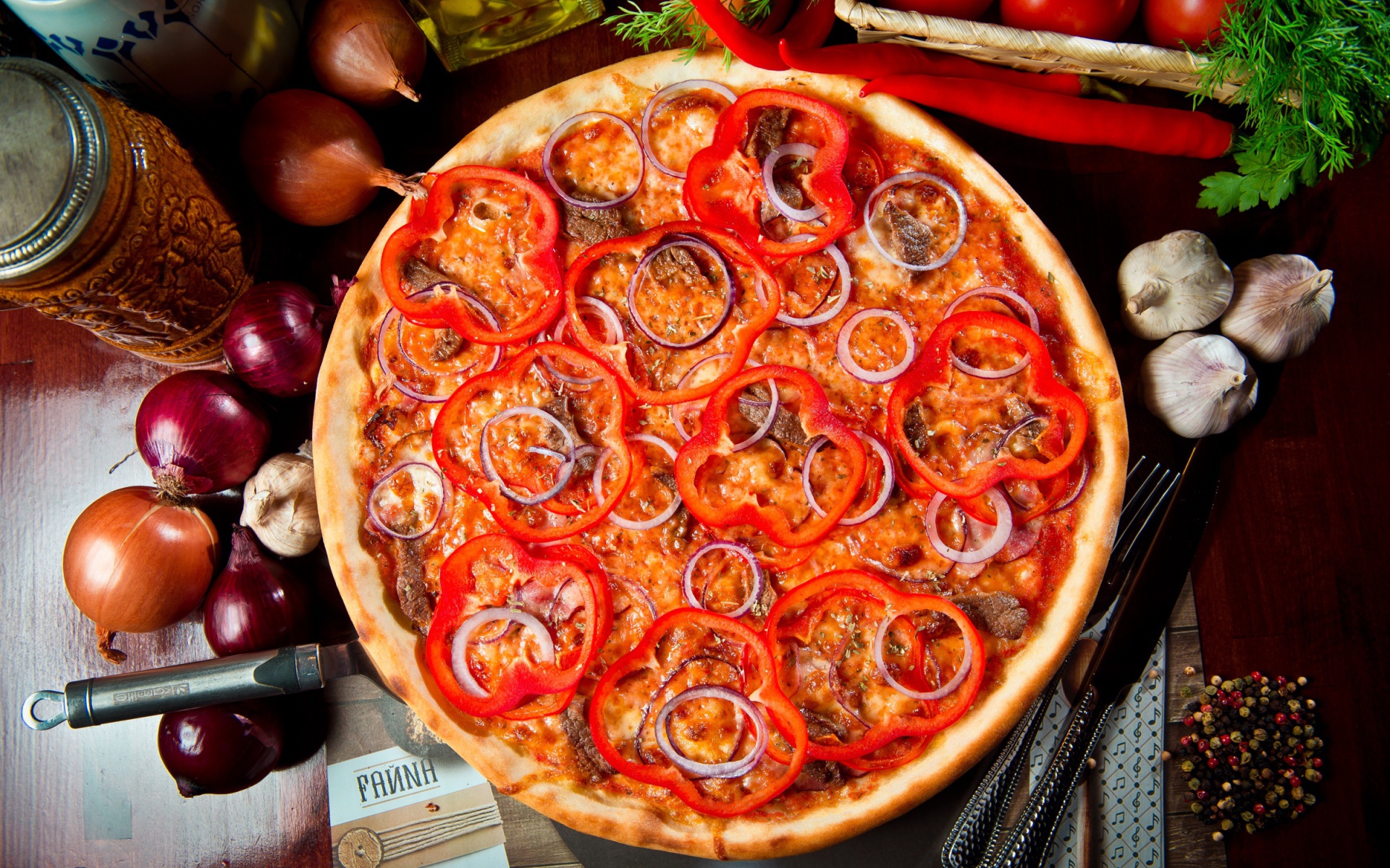 Большая пицца с мясом, луком и болгарским перцем на столе 