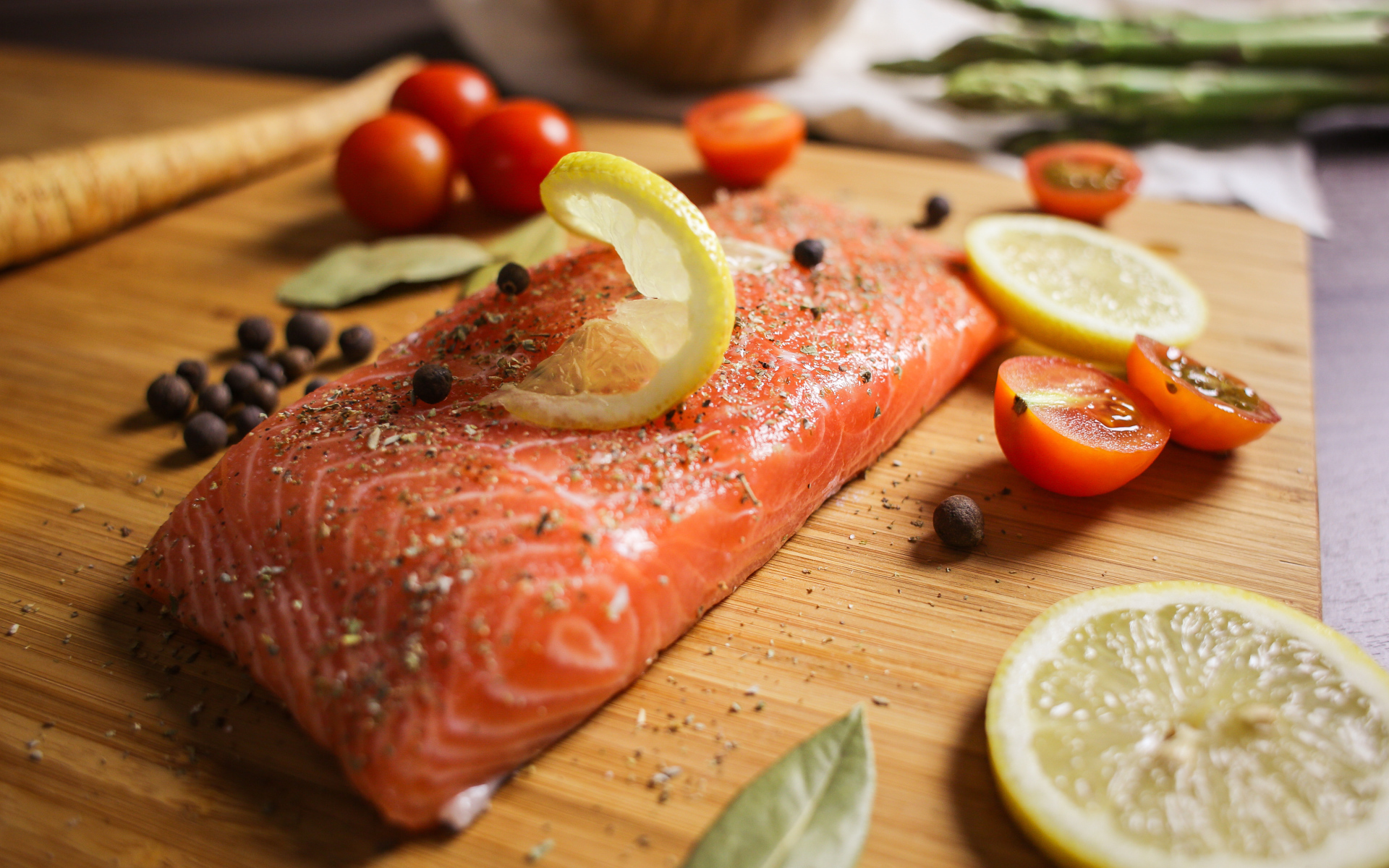 Кусок красной рыбы на доске с лимоном и помидорами