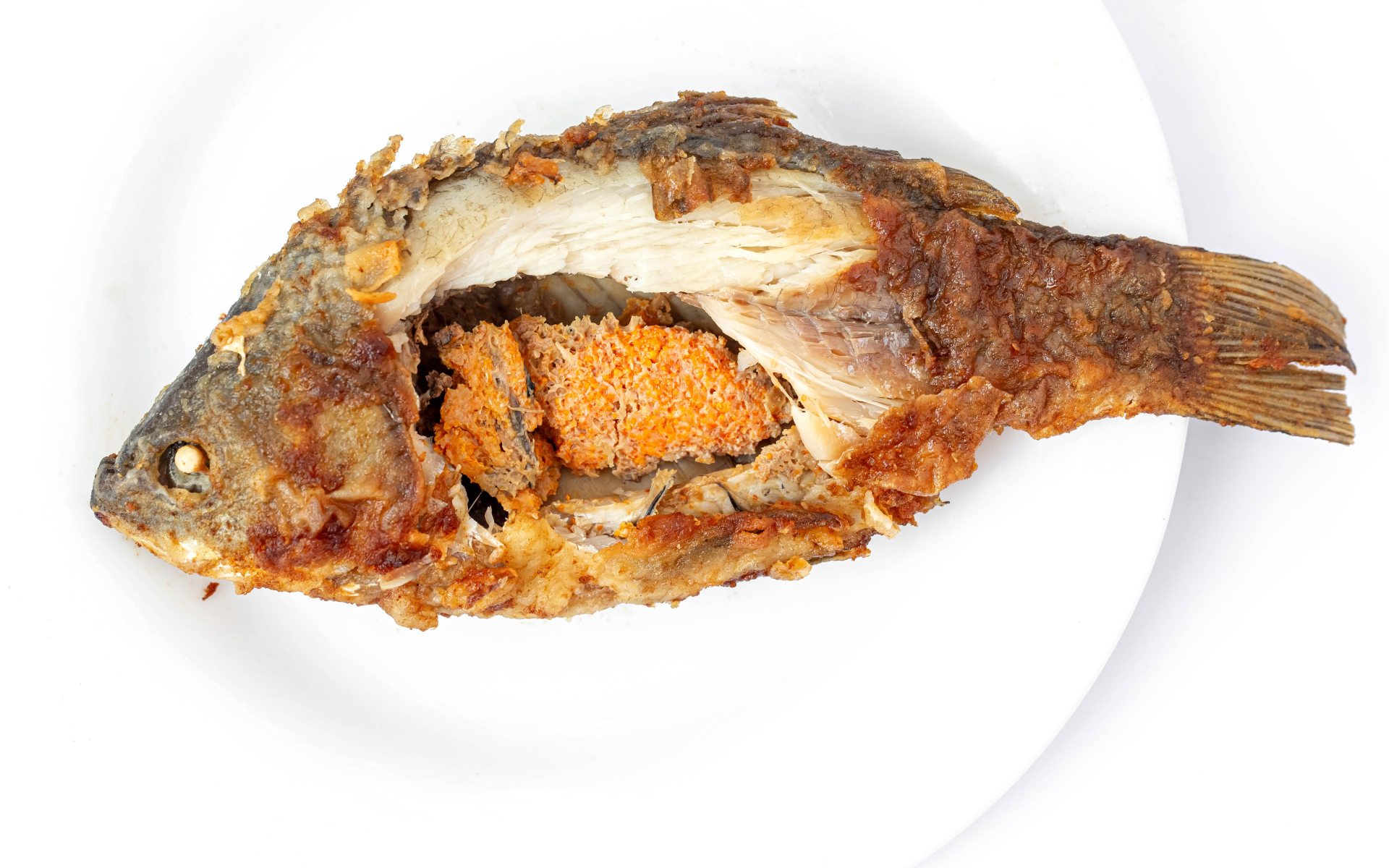 Жареная рыба с икрой внутри на белом фоне