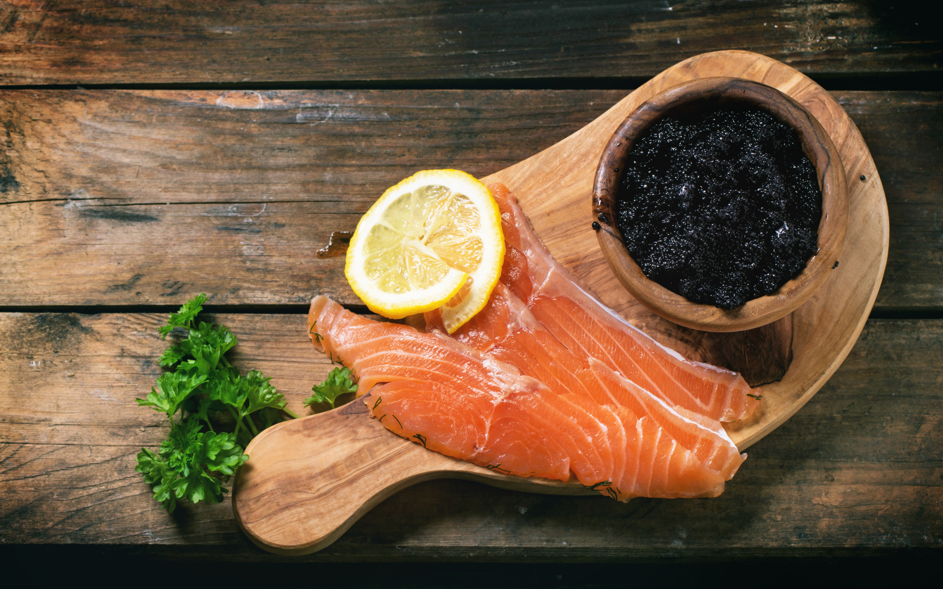 Кусочки красной рыбы с лимоном на столе с черной икрой 