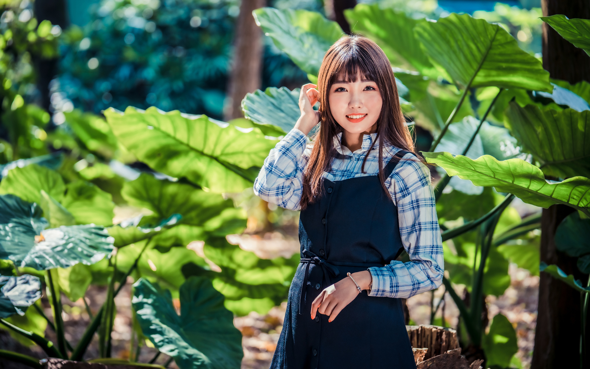 Улыбающаяся девушка азиатка в черном платье стоит в парке