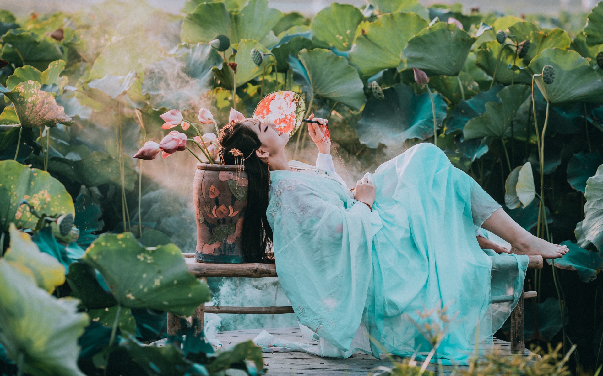 Девушка азиатка в красивом голубом платье на поле лотосов