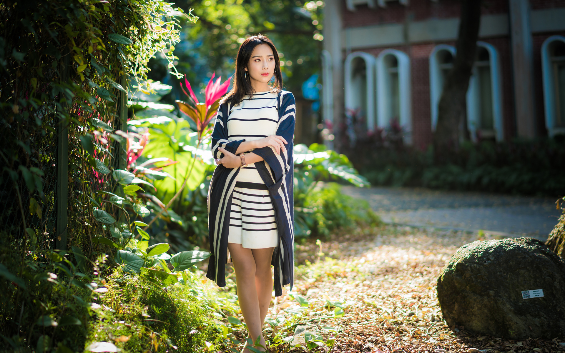 Девушка азиатка идет по улице у забора