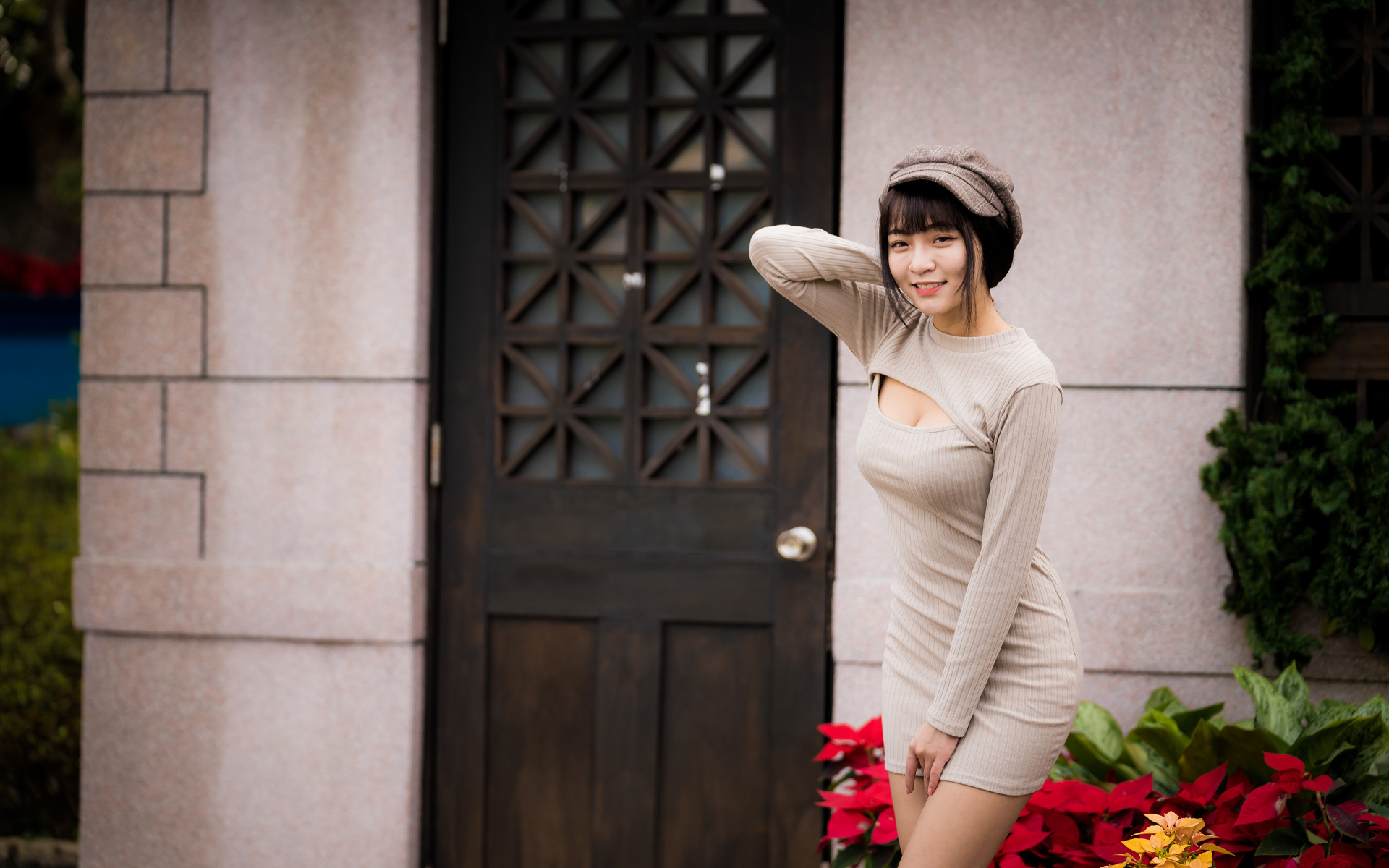 Красивая азиатка в платье стоит у двери 