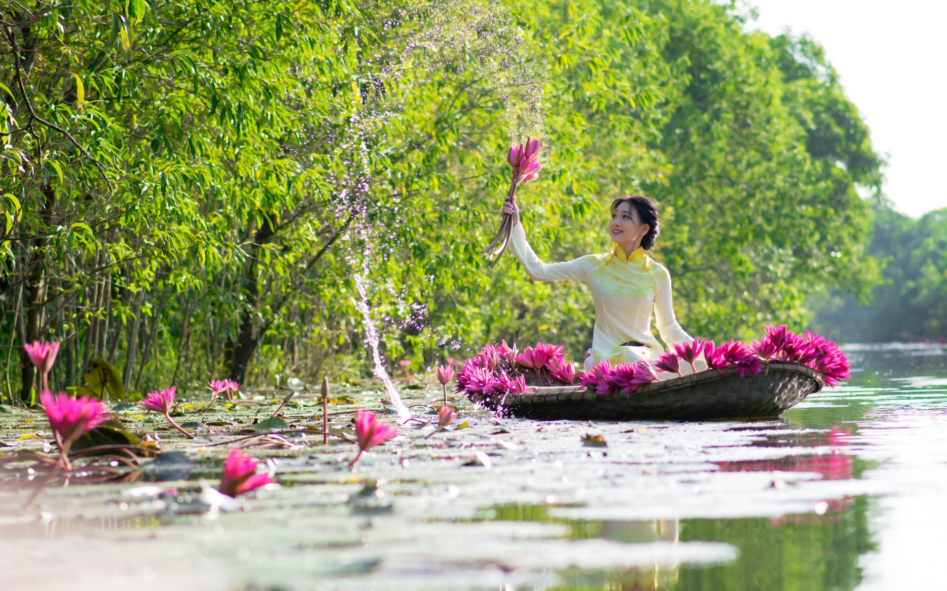 Красивая девушка азиатка на лодке рвет цветы лотоса в реке