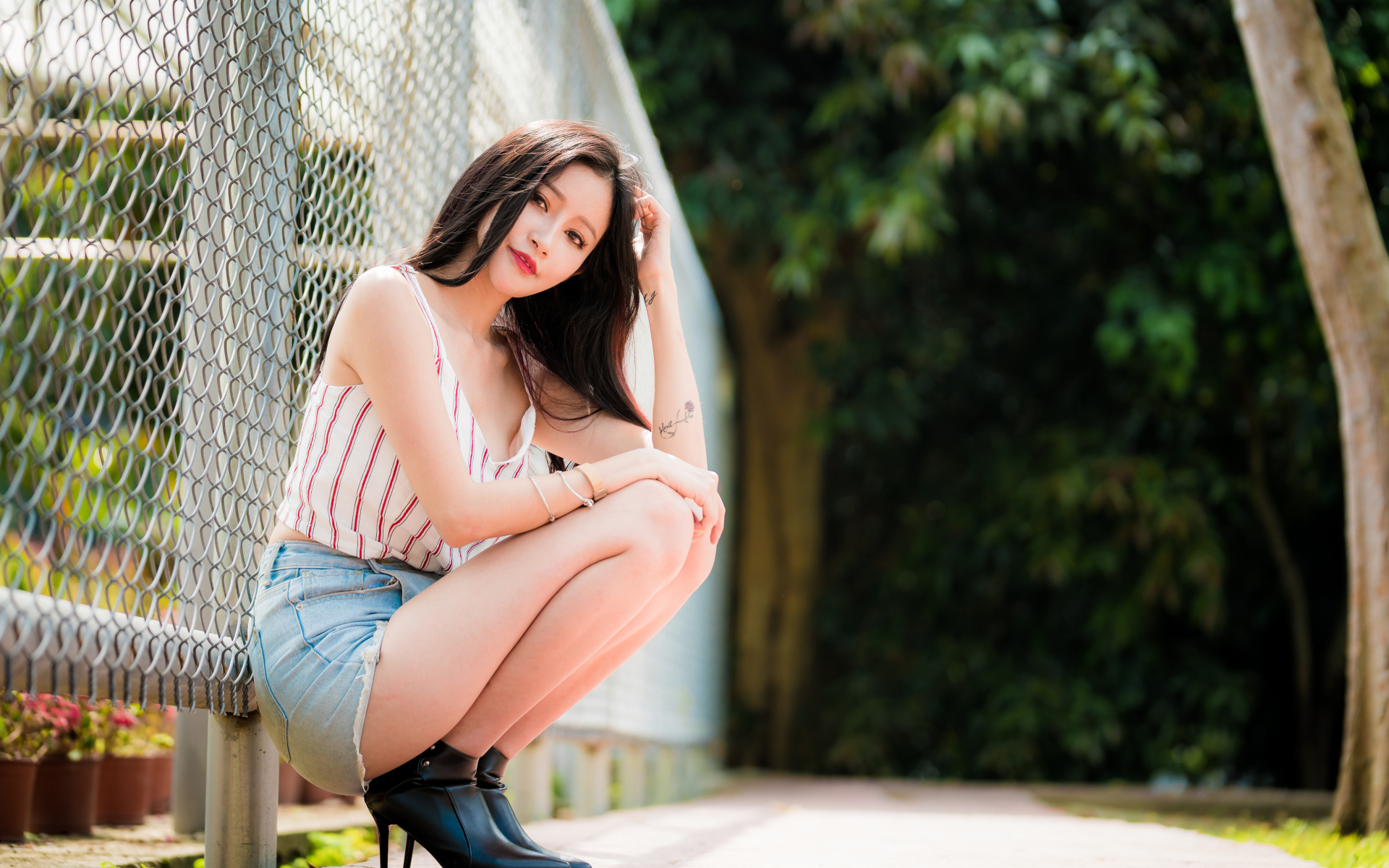 Красивая девушка азиатка сидит у железной сетки