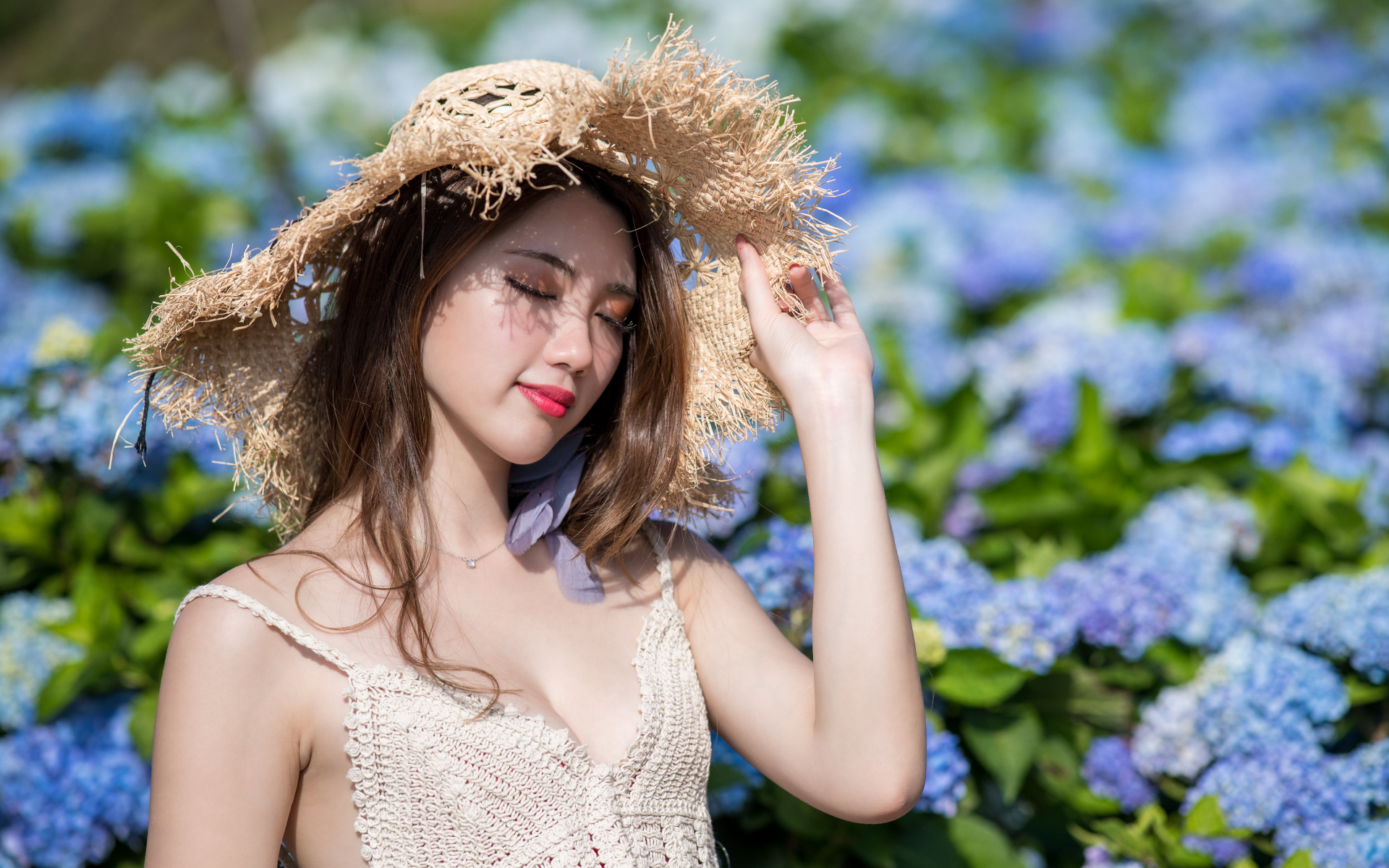 Красивая девушка азиатка с закрытыми глазами на фоне цветов гортензии