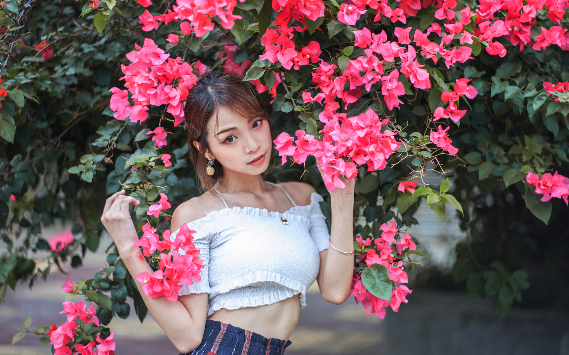 Красивая азиатка стоит у дерева с красными цветами