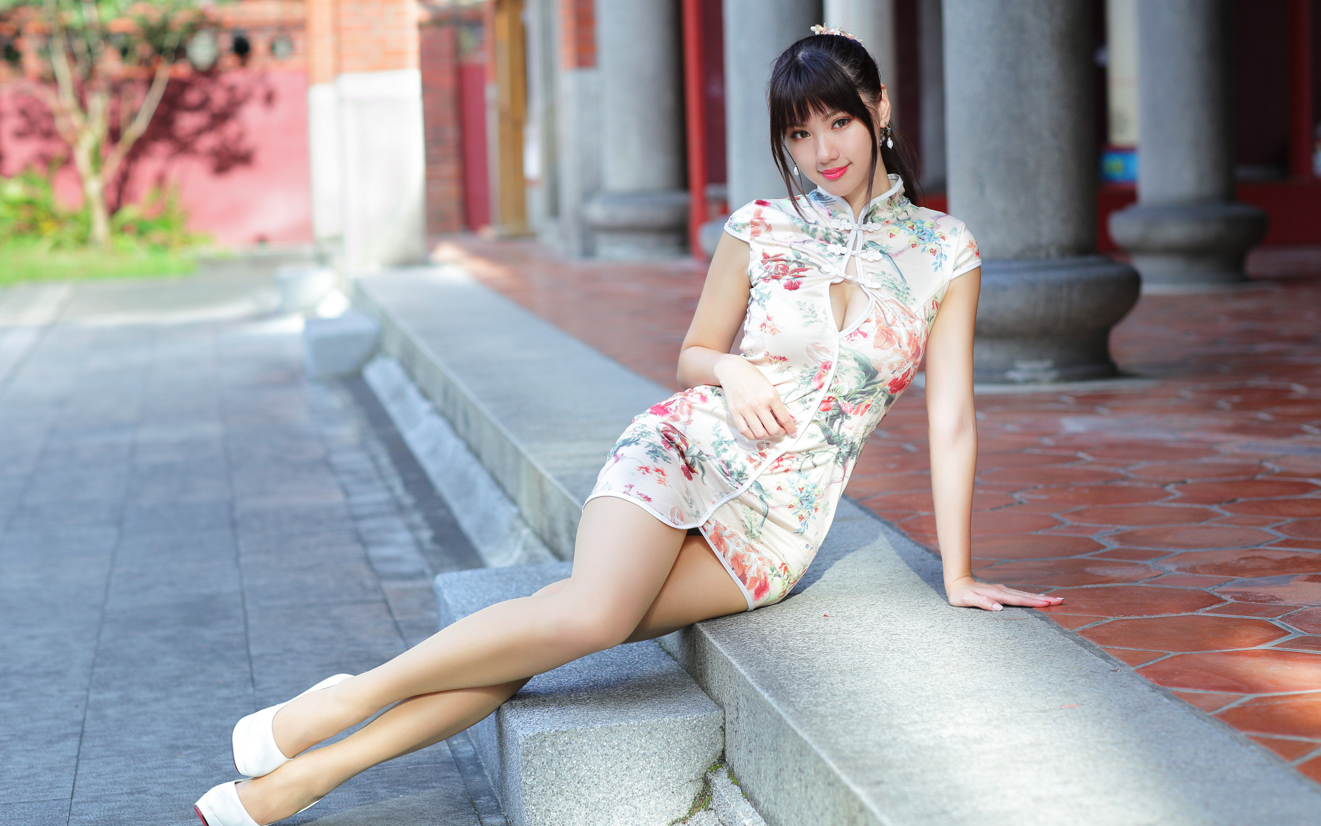Красивая девушка азиатка в платье сидит на ступеньках