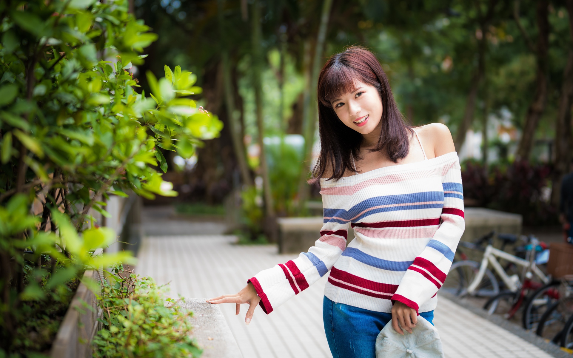Красивая азиатка в полосатом свитере в парке