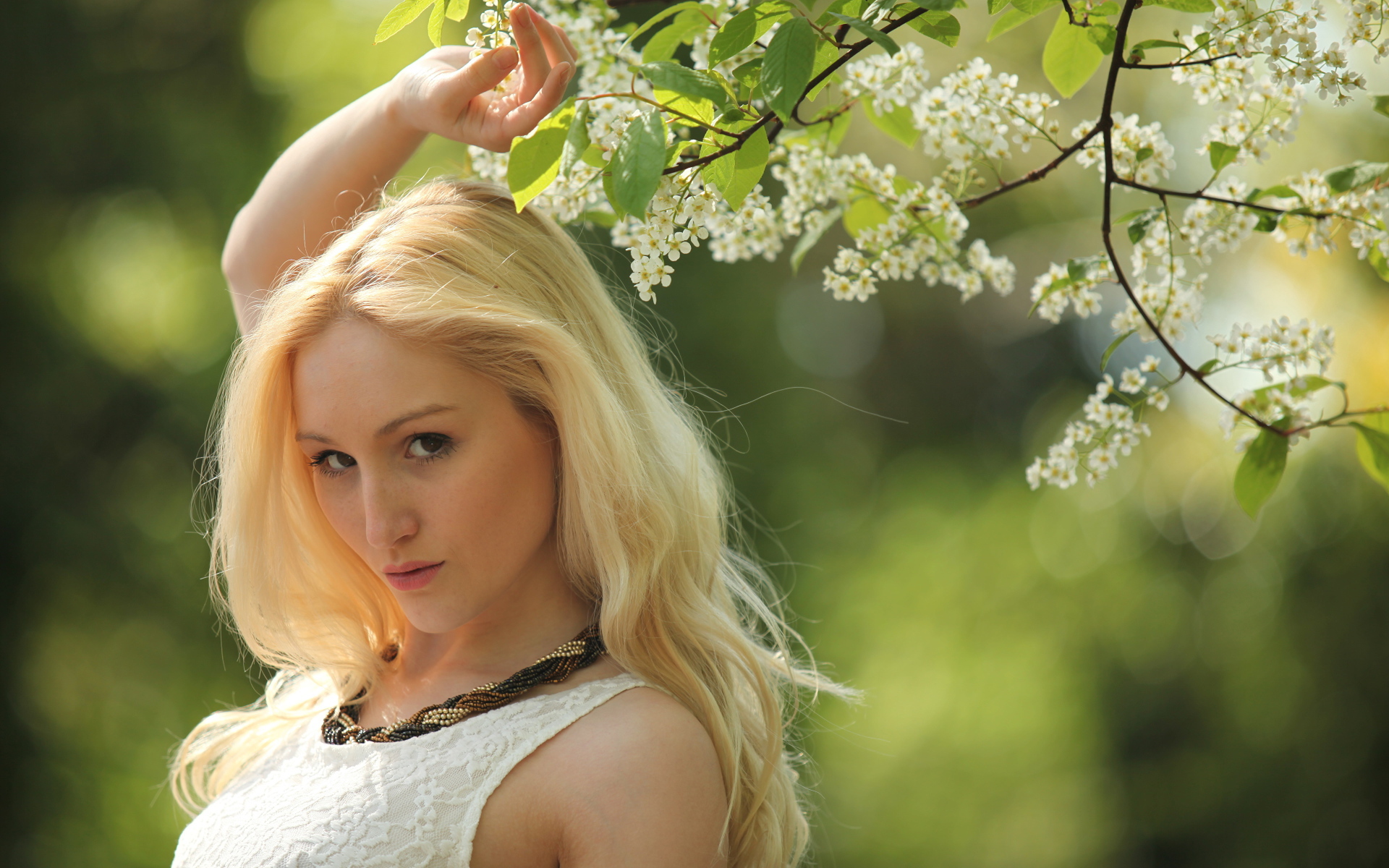 Красивая блондинка у ветки с белыми цветами
