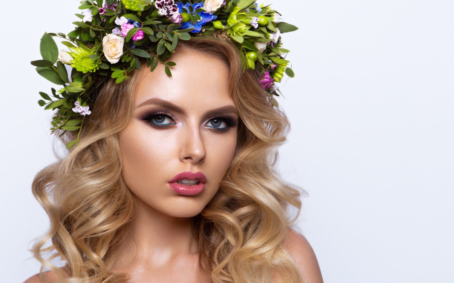 Красивая блондинка с венком из живых цветов на белом фоне