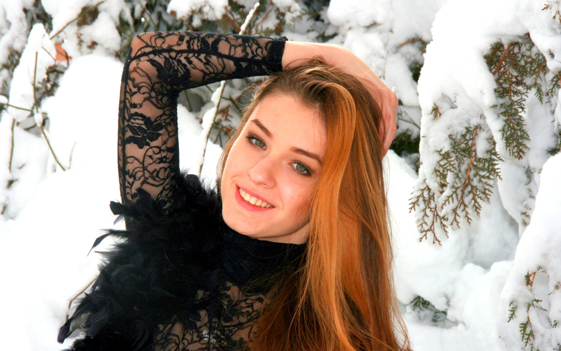 Красивая рыжеволосая девушка у заснеженной туи