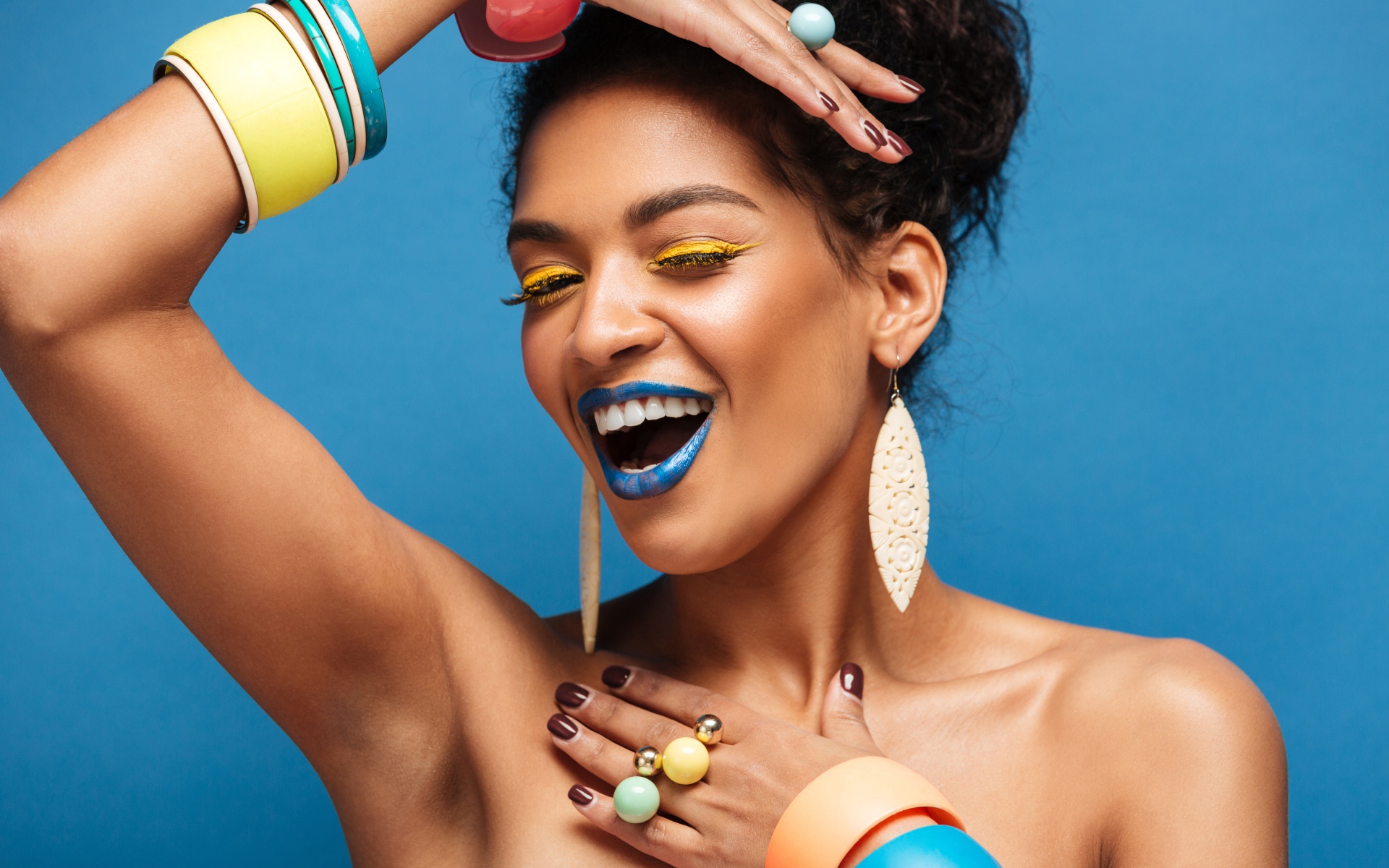 Красивая молодая девушка с ярким разноцветным макияжем на голубом фоне