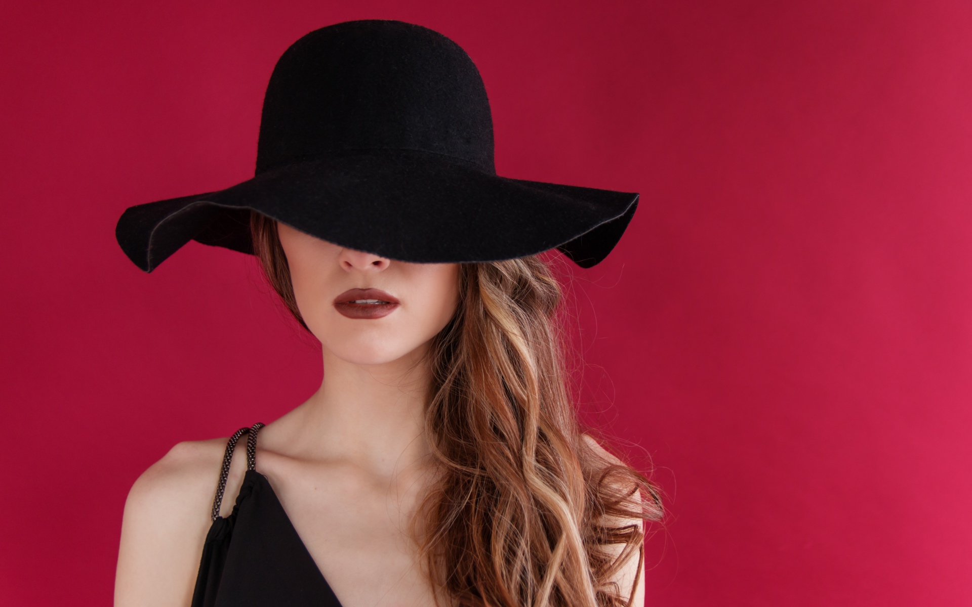 Большая черная шляпа закрывает лицо девушки
