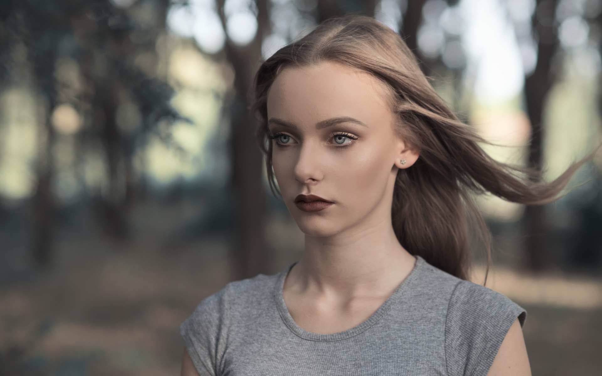 Голубоглазая девушка в серой майке в парке 