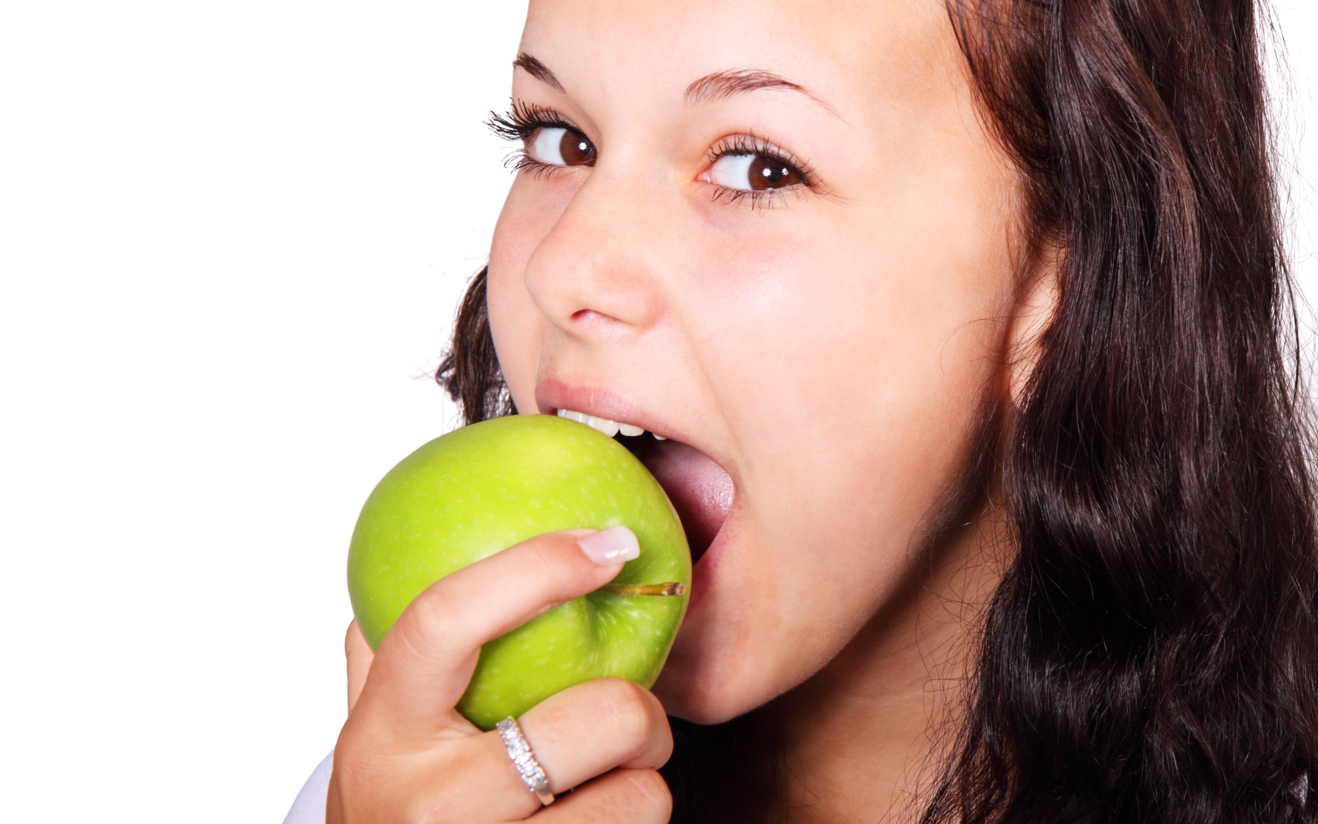 Кареглазая девушка ест зеленое яблоко