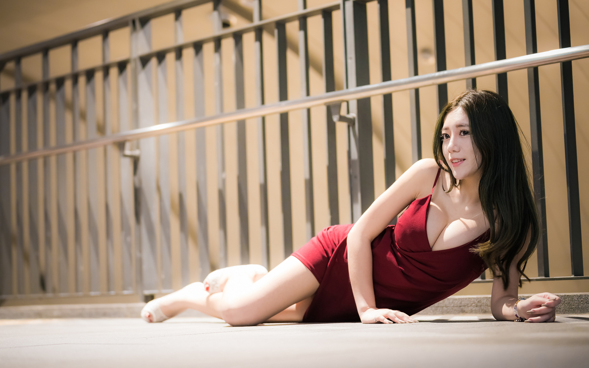 Милая девушка азиатка в красном платье лежит на земле