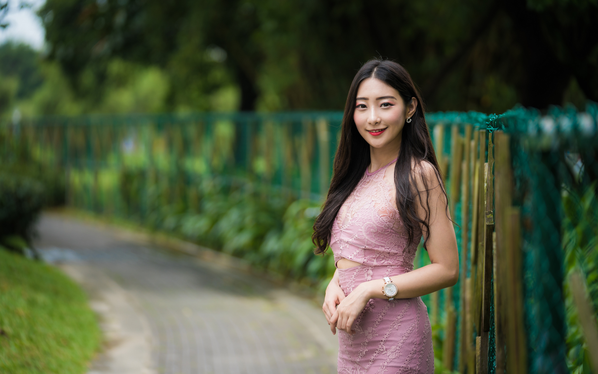 Милая улыбающаяся азиатка в костюме у забора