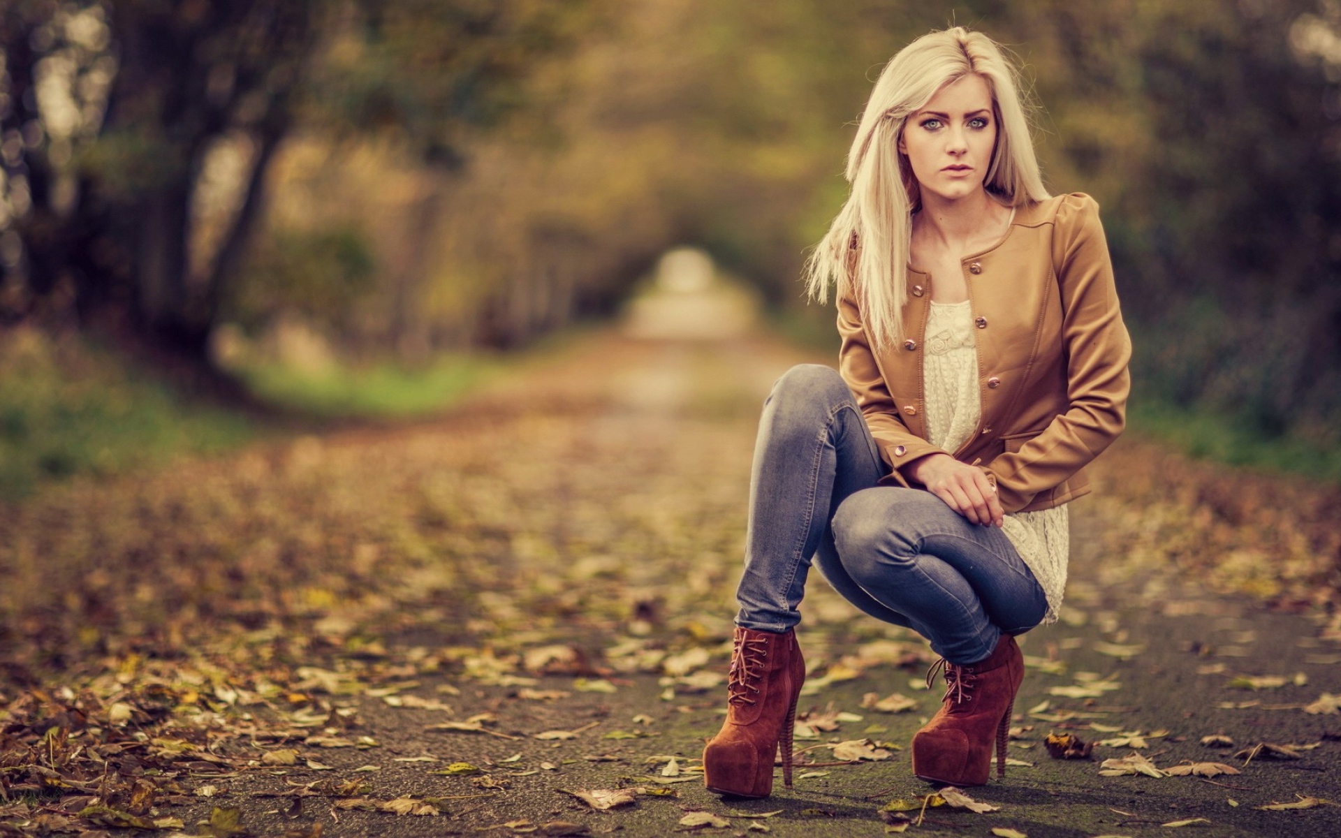 Девушка на высоких каблуках сидит на корточках в парке