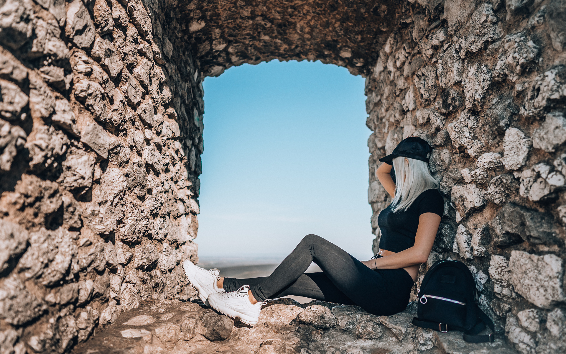 Девушка сидит в окне старого здания 