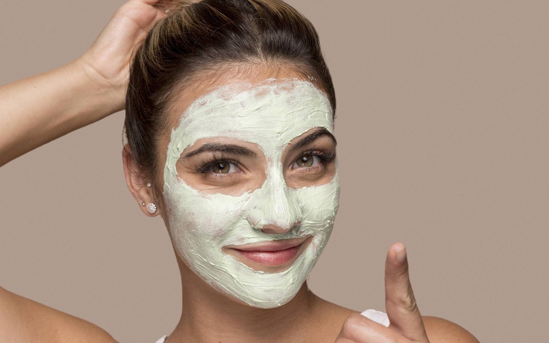 Девушка с завязанными волосами с косметической маской на лице