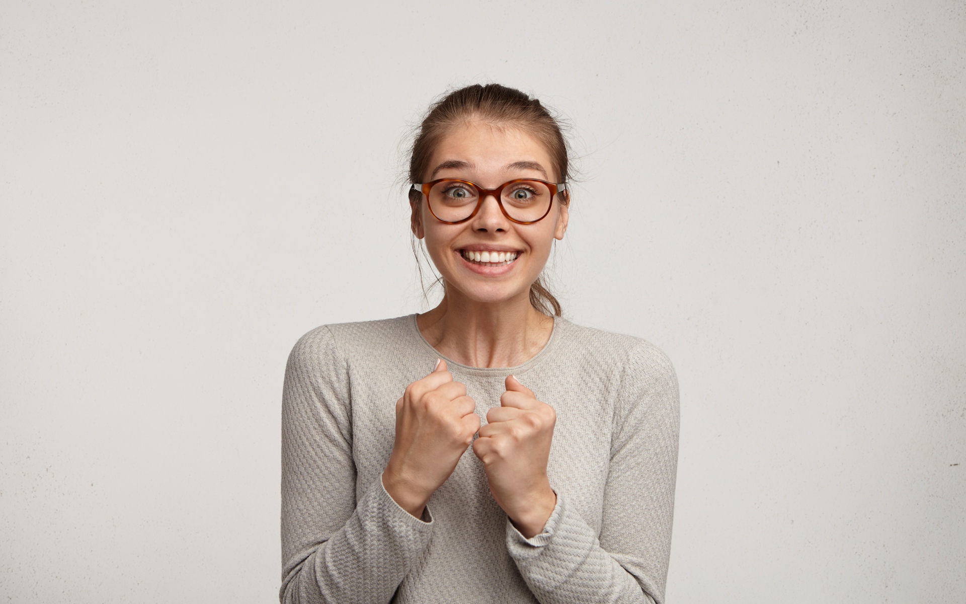 Радостная девушка в очках для зрения на сером фоне 