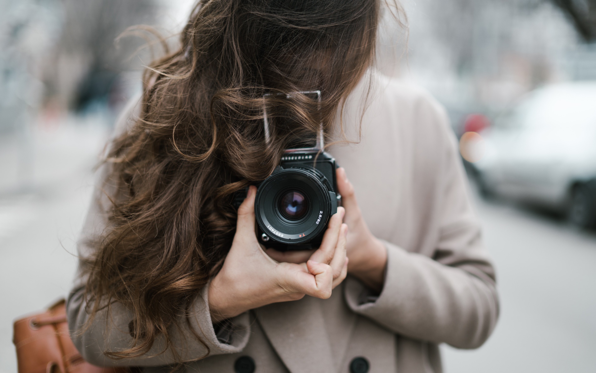 Длинноволосая девушка с фотоаппаратом в руках 