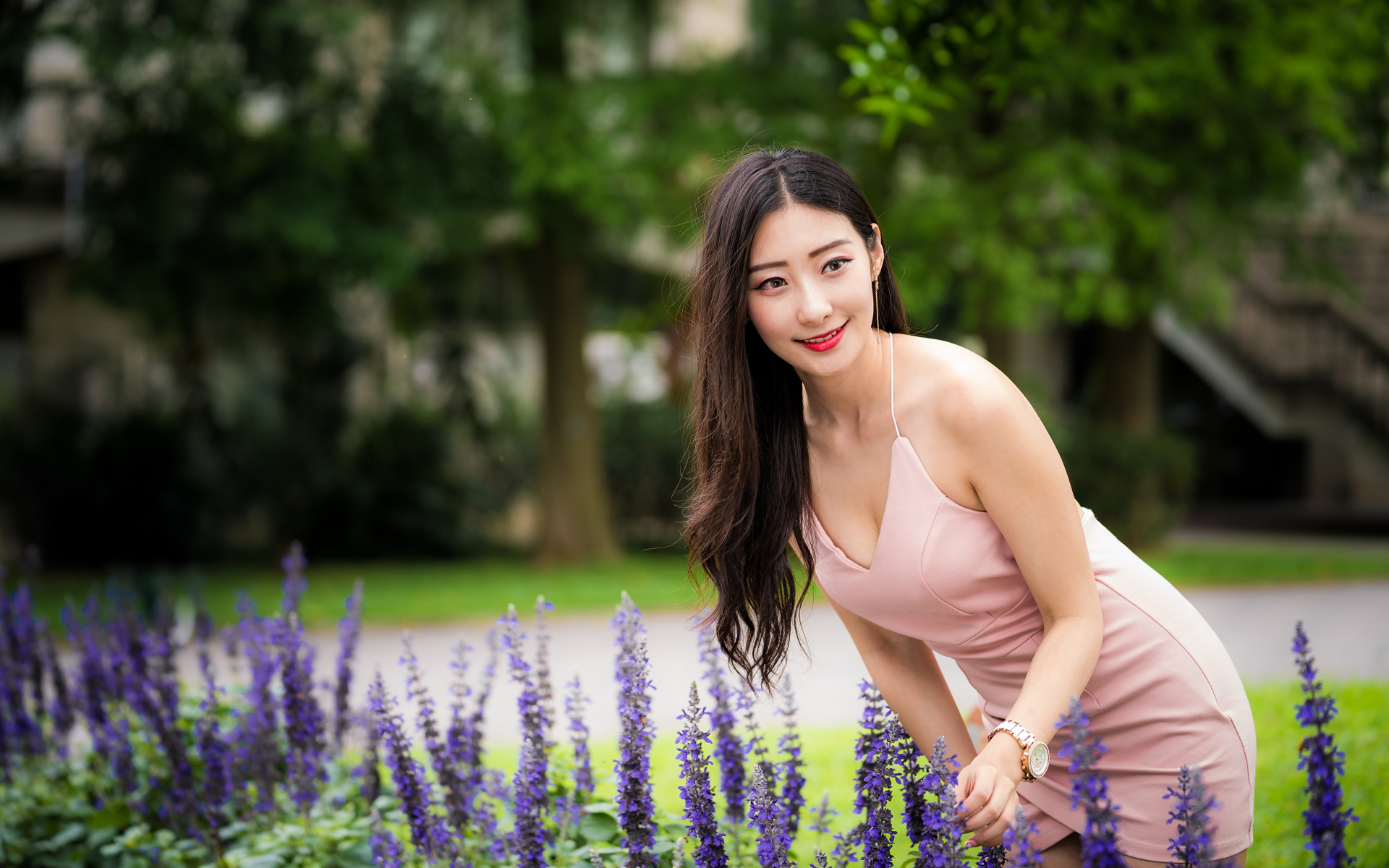 Милая девушка Азиатка в розовом платье у синих цветов