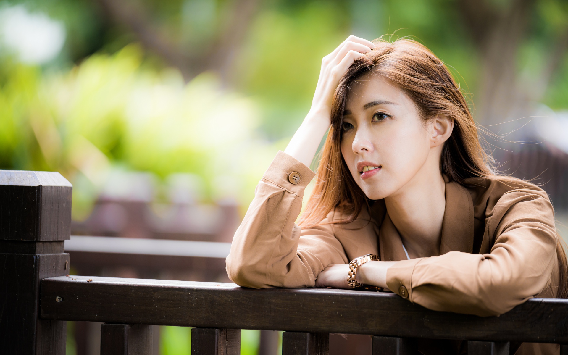 Грустная девушка азиатка стоит у деревянных перил 