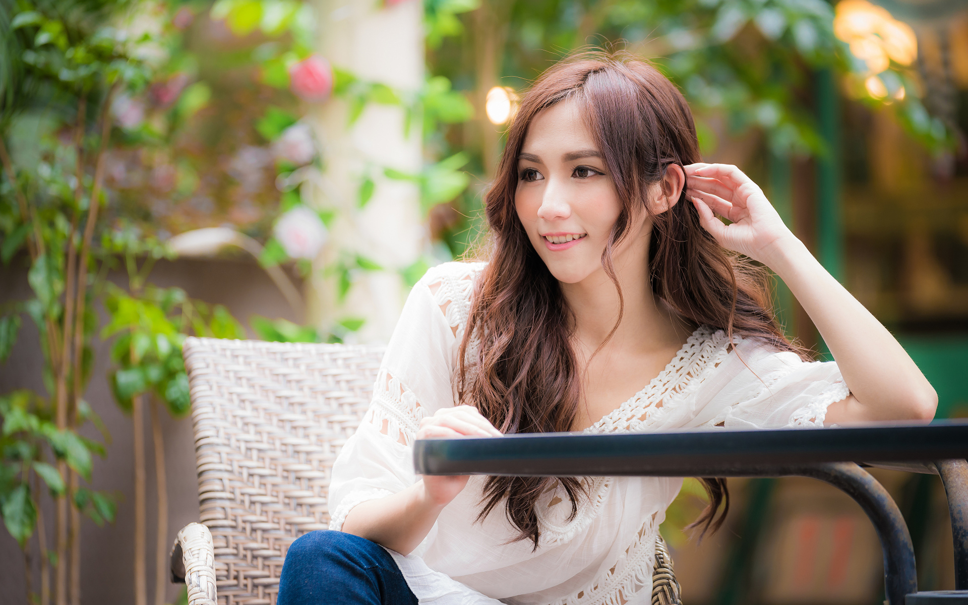 Улыбающаяся девушка азиатка сидит за столом в кафе