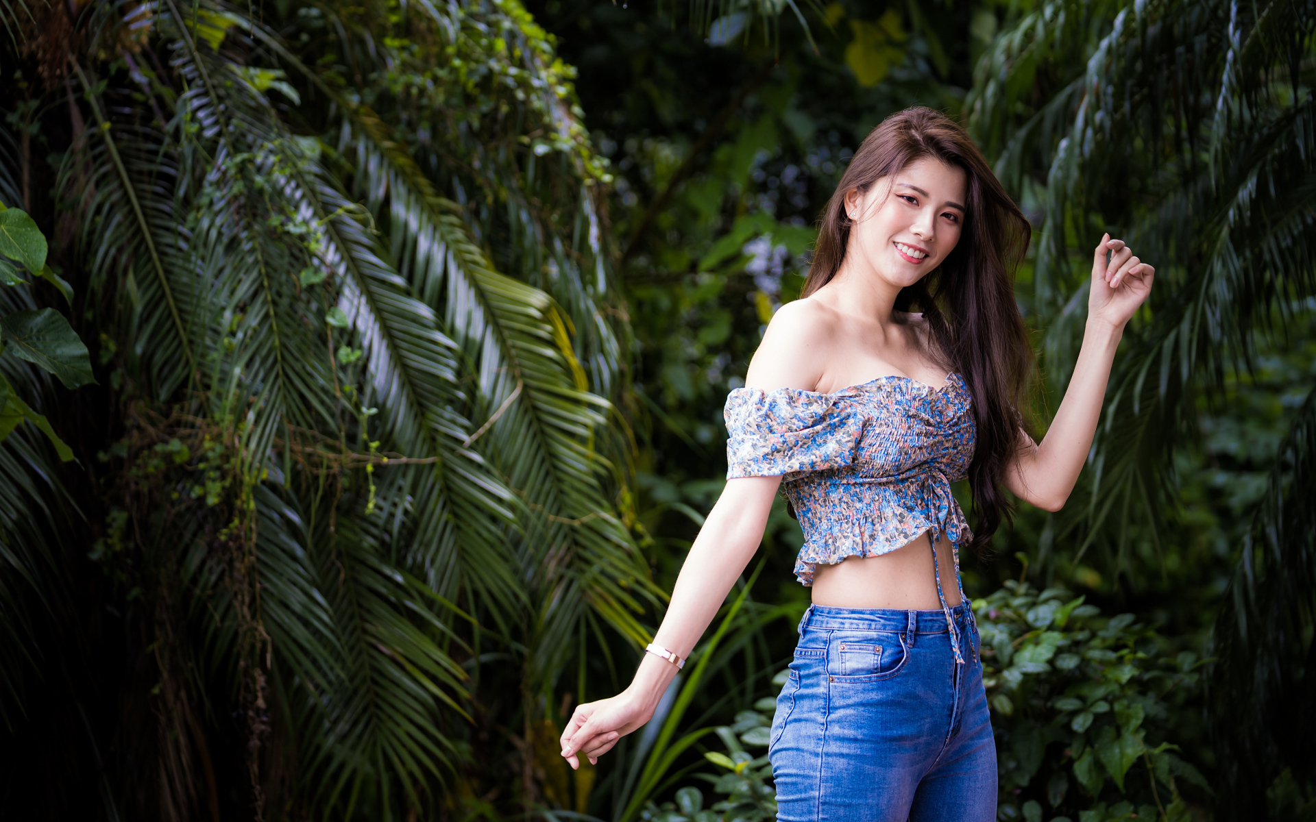 Улыбающаяся азиатка на фоне зеленых листьев