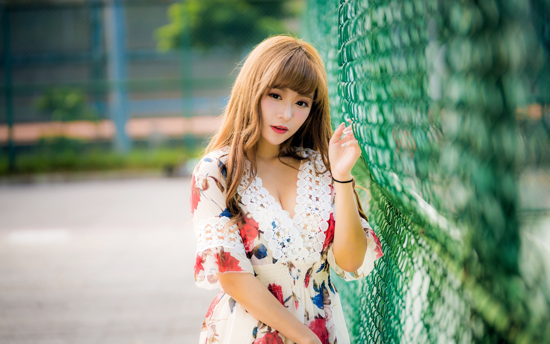 Молодая азиатка в платье у зеленой сетке 