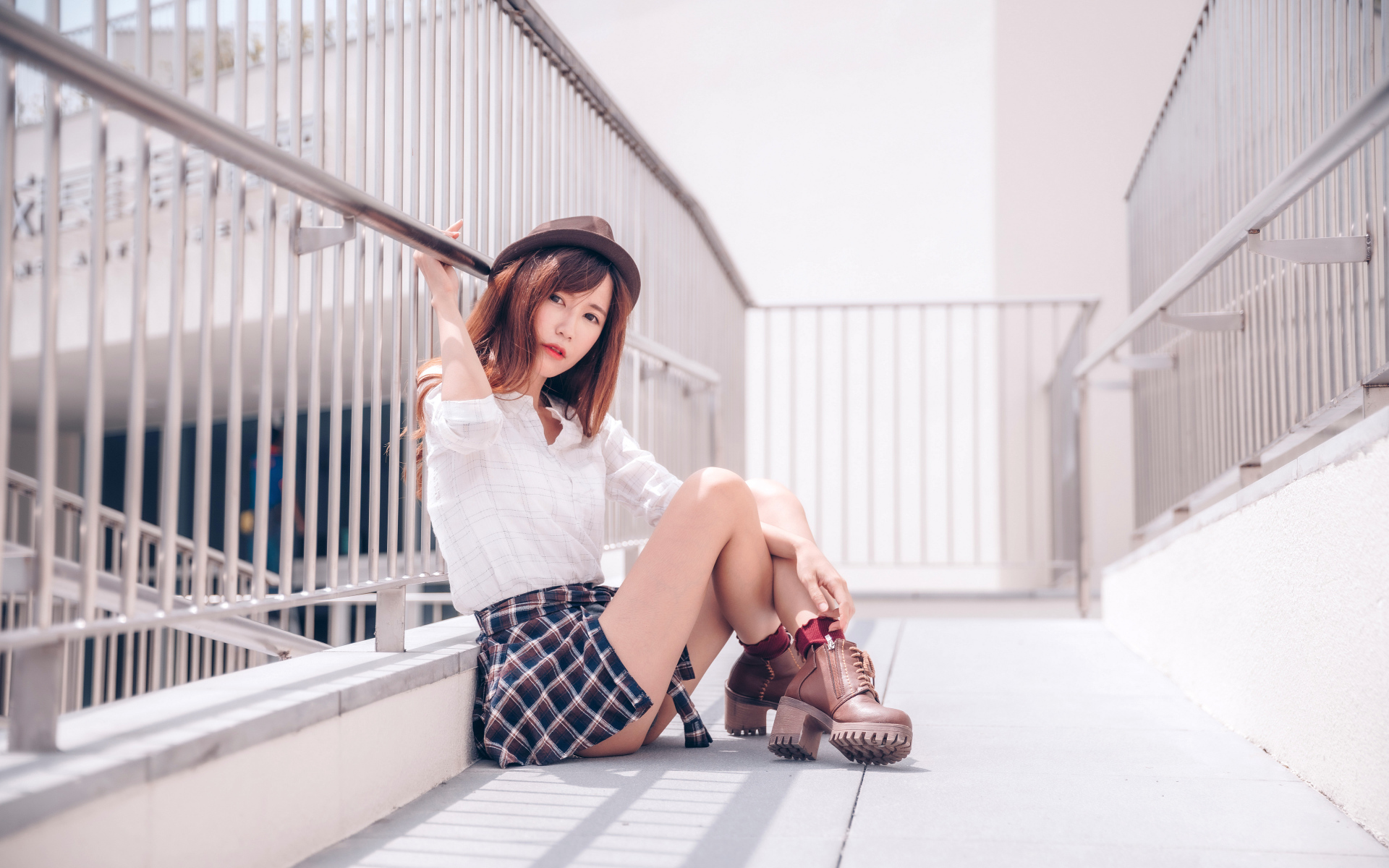 Молодая азиатка в короткой юбке сидит у перил 