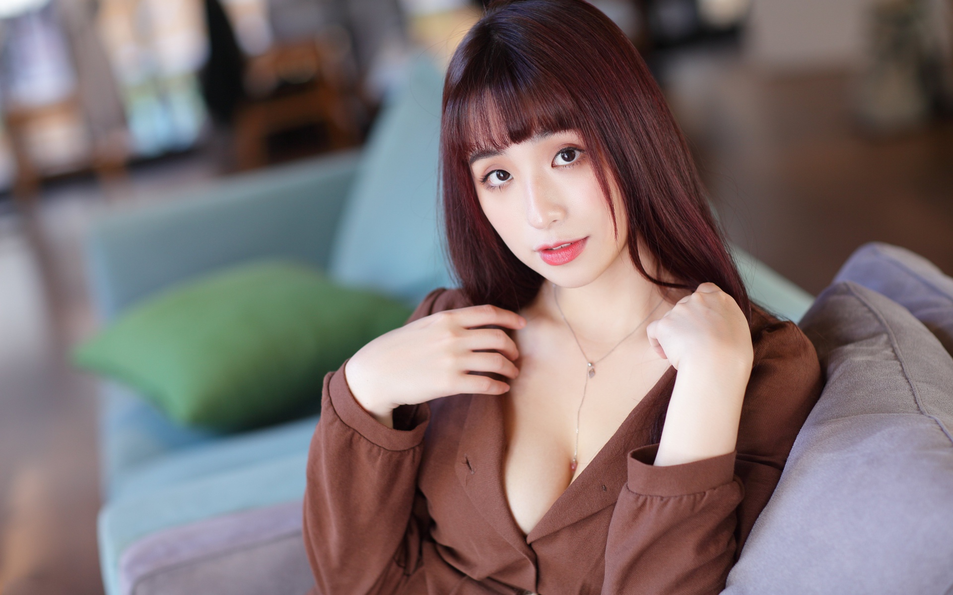 Молодая азиатка сидит на диване 