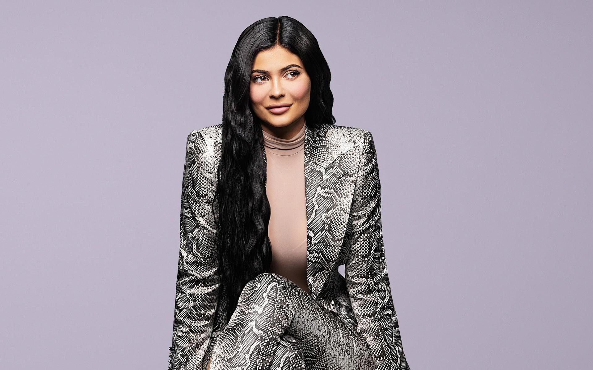 Длинноволосая модель Кайли Дженнер в костюме на сером фоне