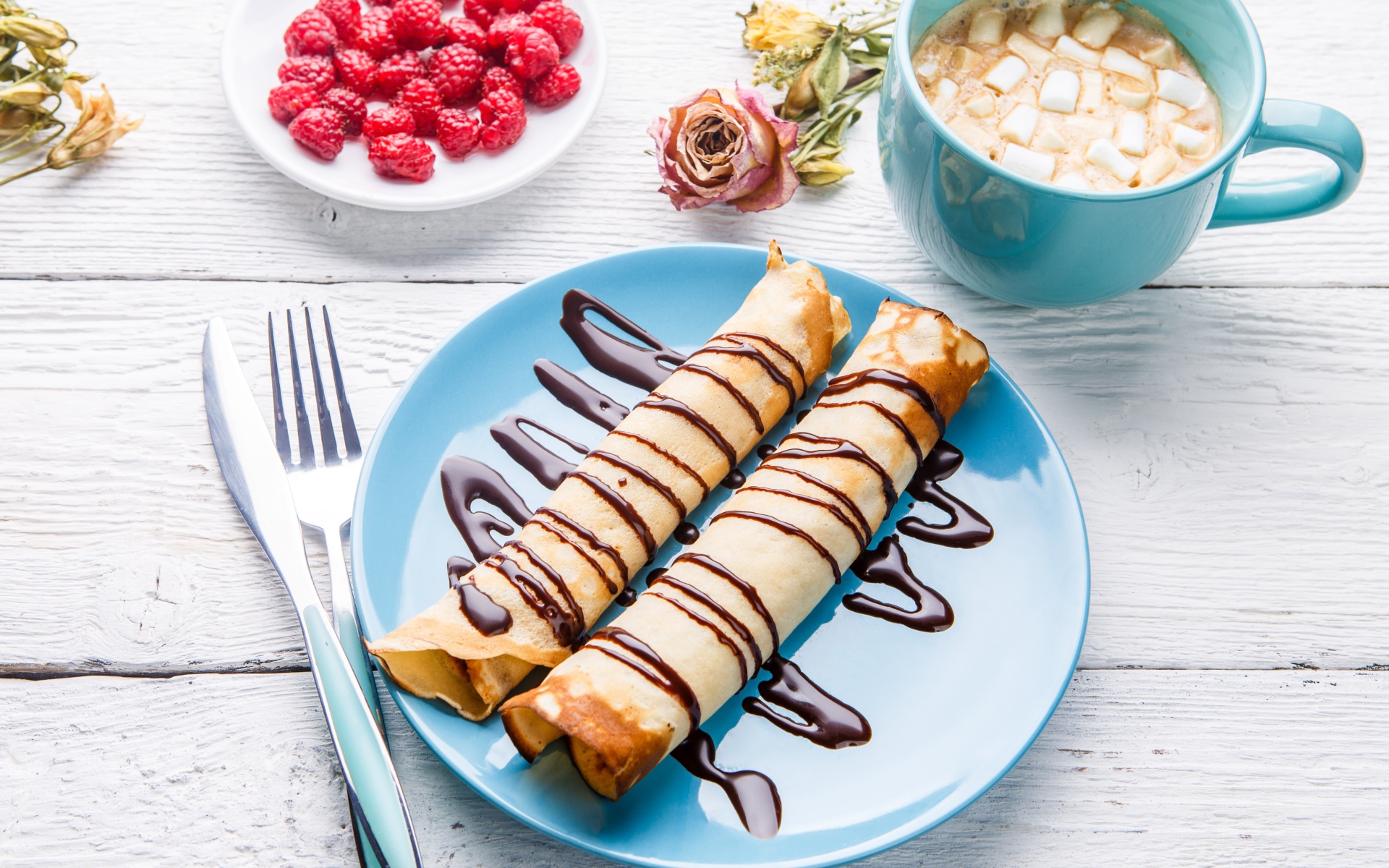 Тонкие блины с шоколадом на столе с ягодами малины и какао 