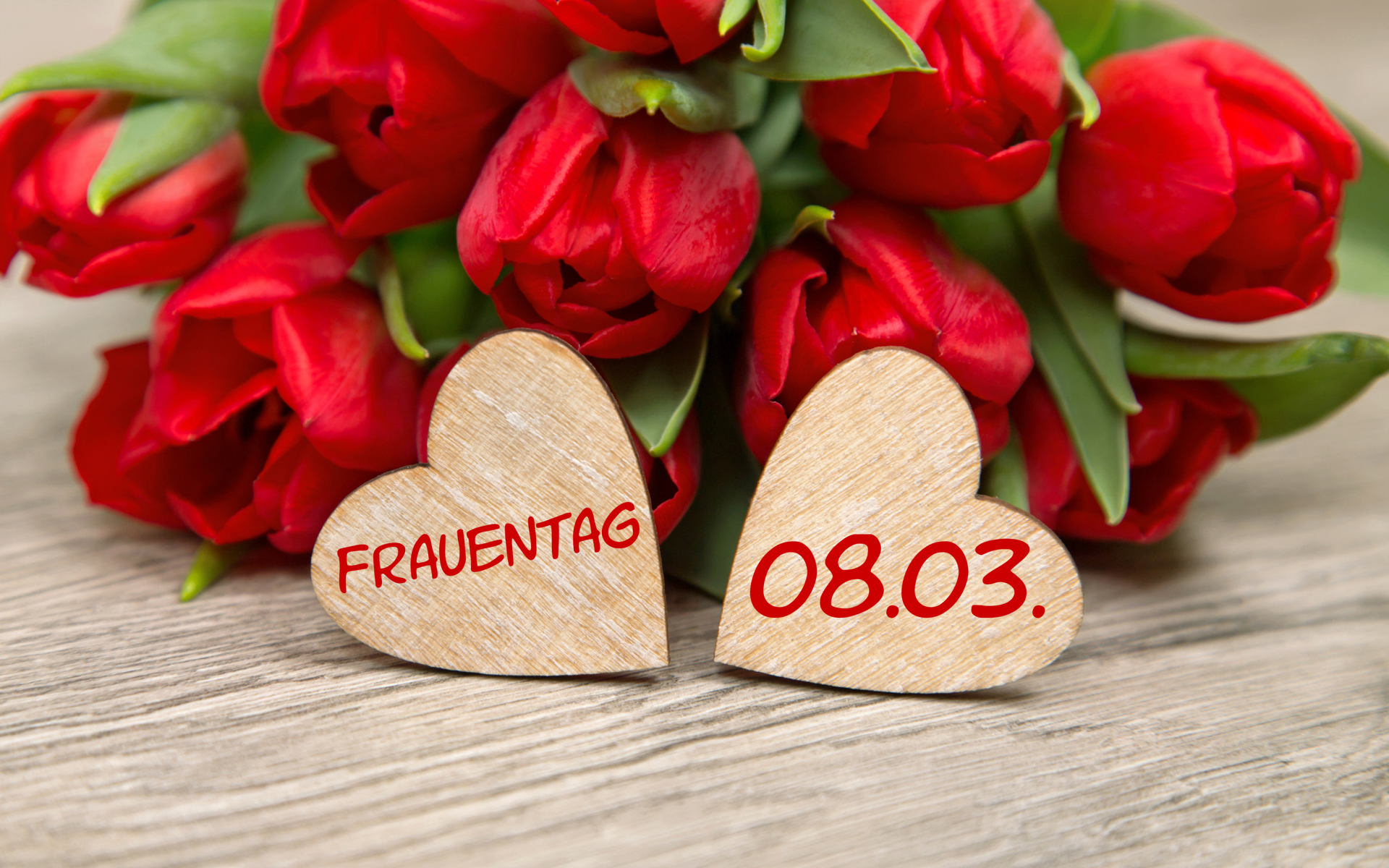 Два сердечка на столе с букетом красных тюльпанов на 8 марта 