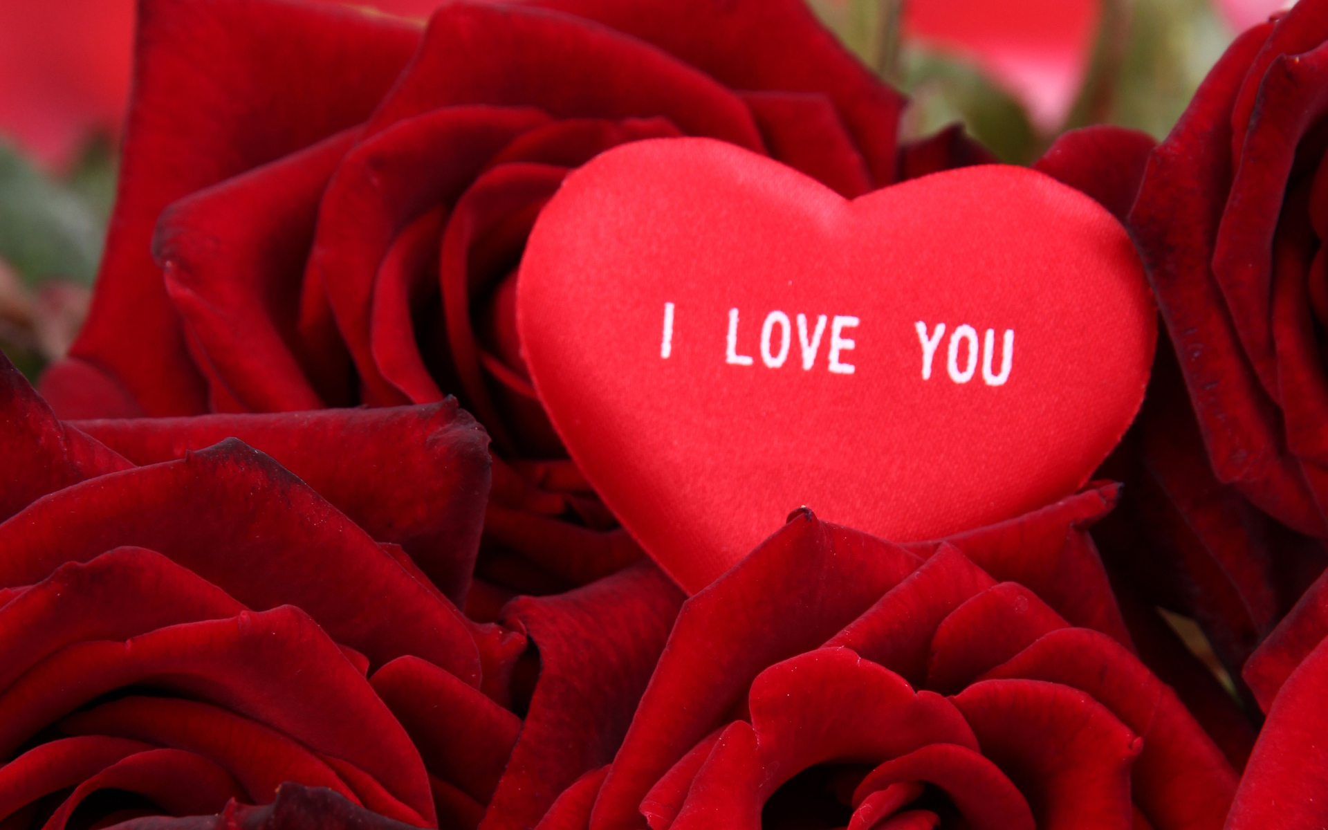 Маленькое сердце лежит на букете красных роз 