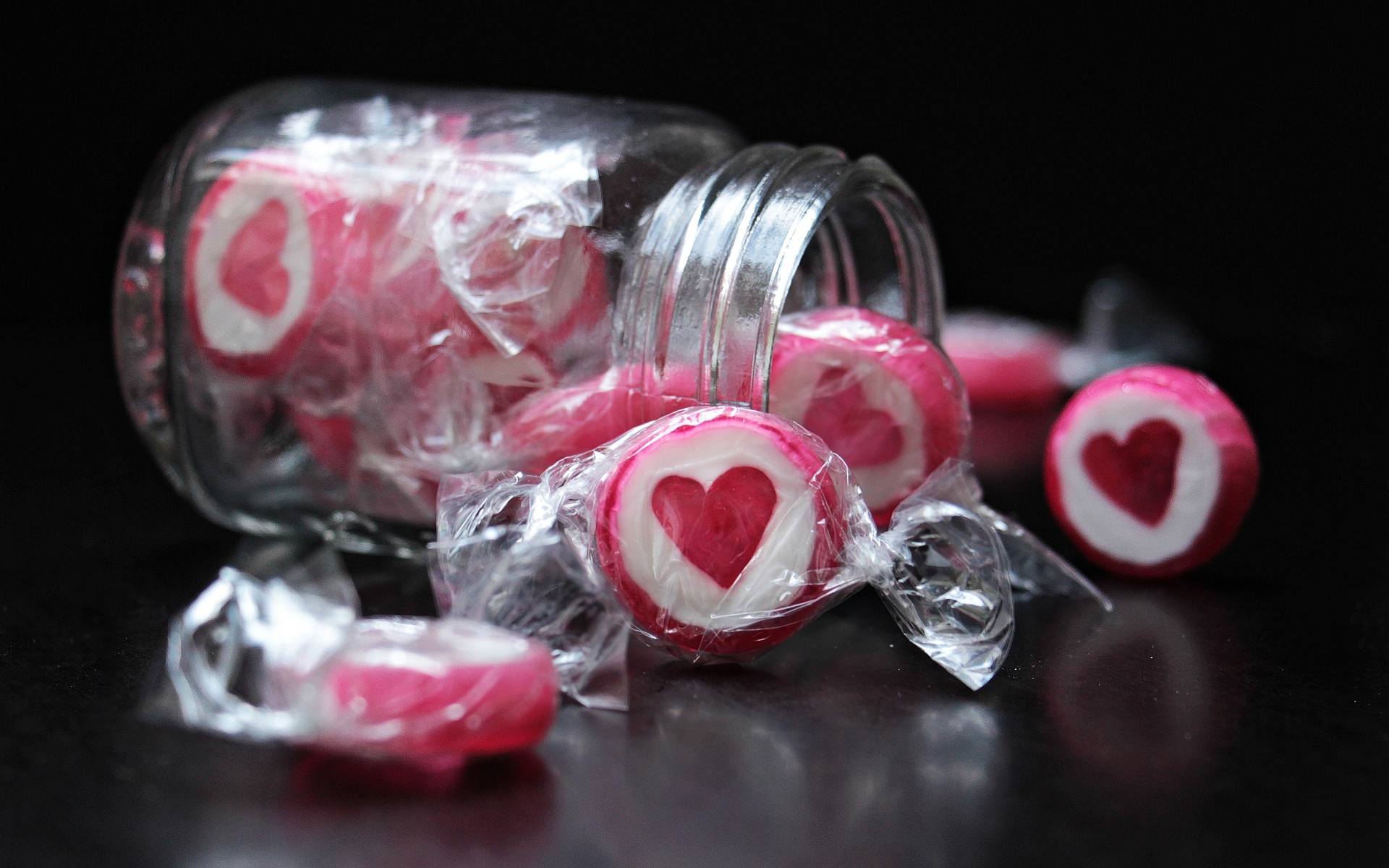 Конфеты с сердцем в стеклянной банке на черном фоне