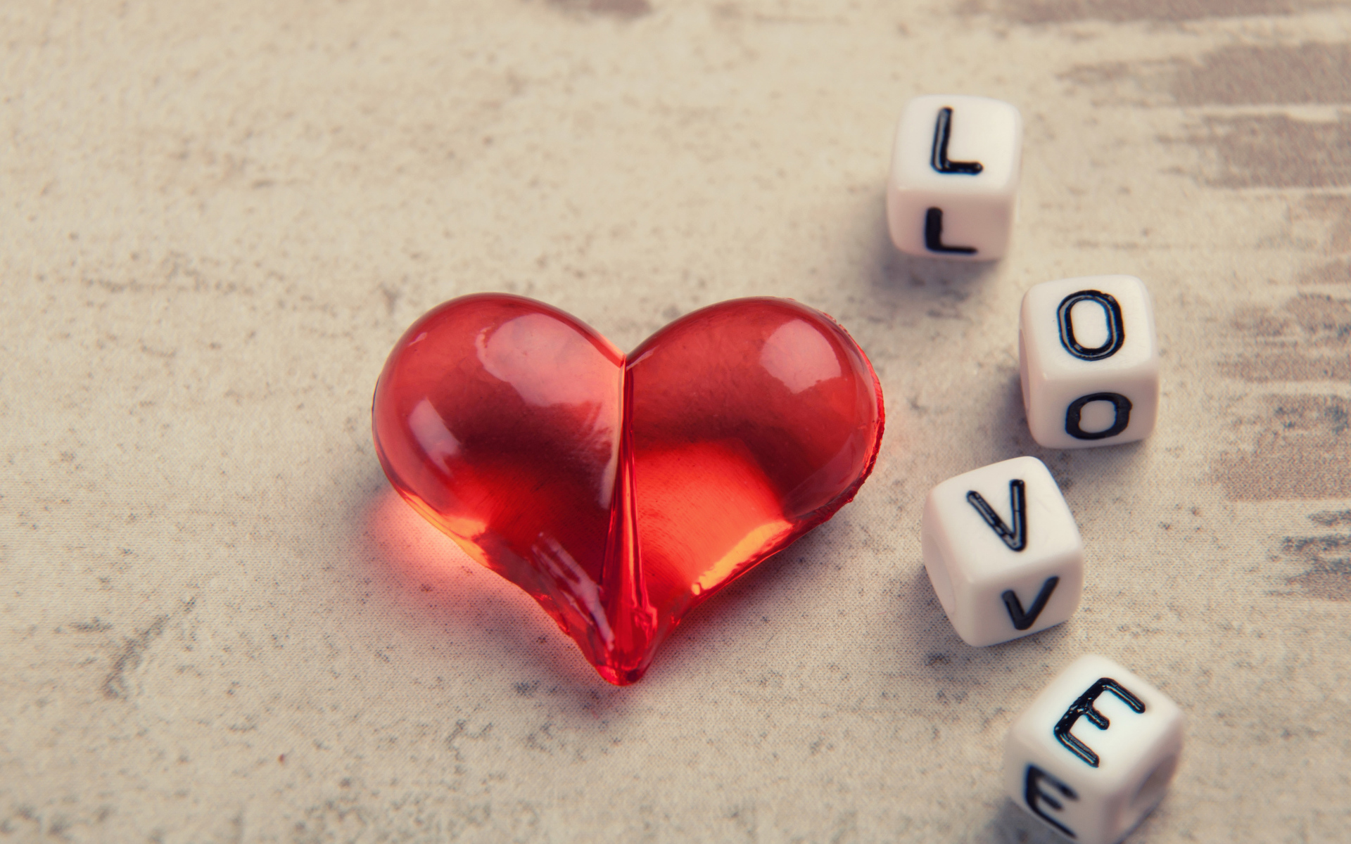 Красное стеклянное сердце на столе с кубиками