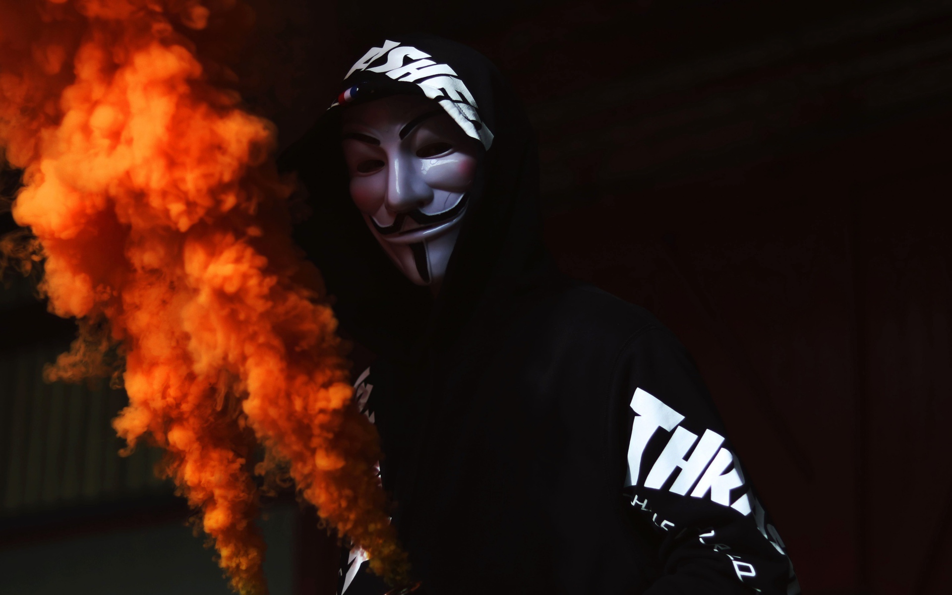 Мужчина в маске анонимуса с дымовой шашкой в руке