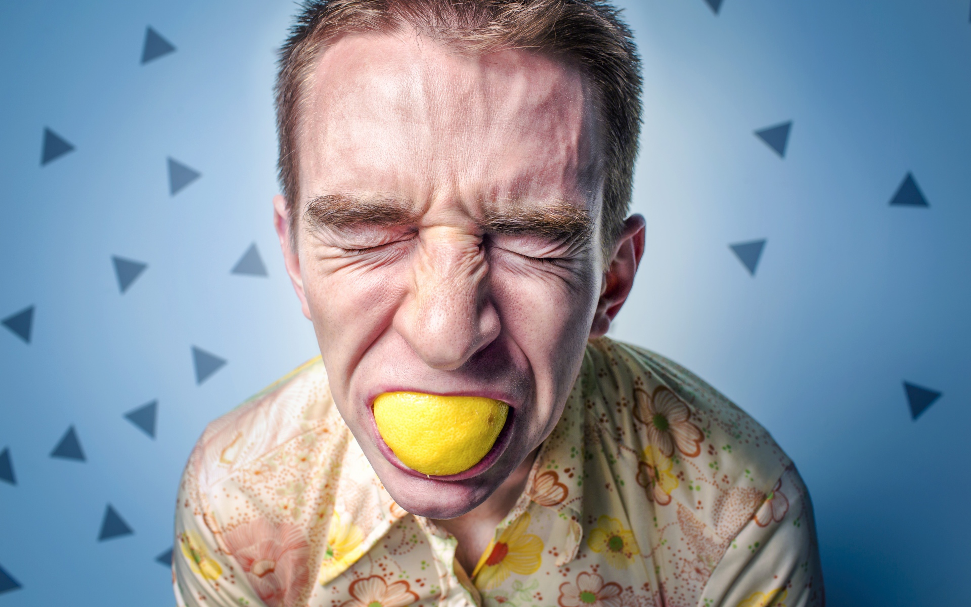 Мужчина с закрытыми глазами ест лимон 