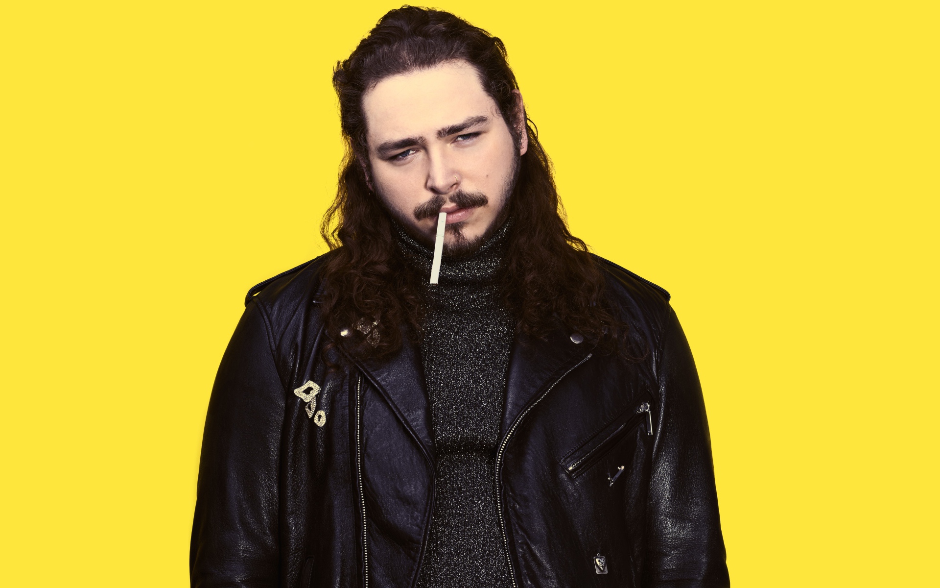 Американский рэпер Post Malone в черной куртке на желтом фоне